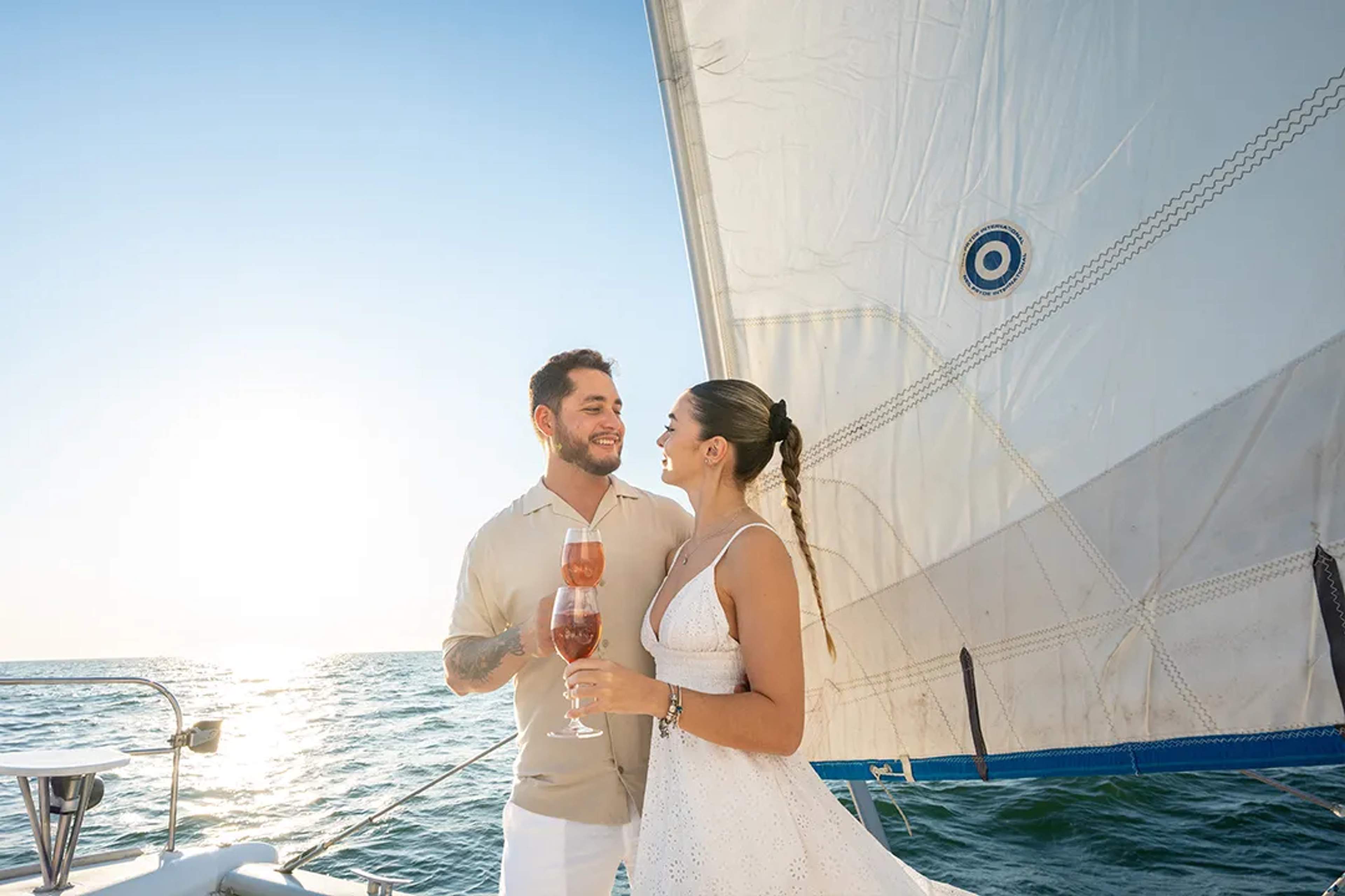 Couple toasting with champagne during a romantic Sunset Sailing experience in Los Cabos with ocean views