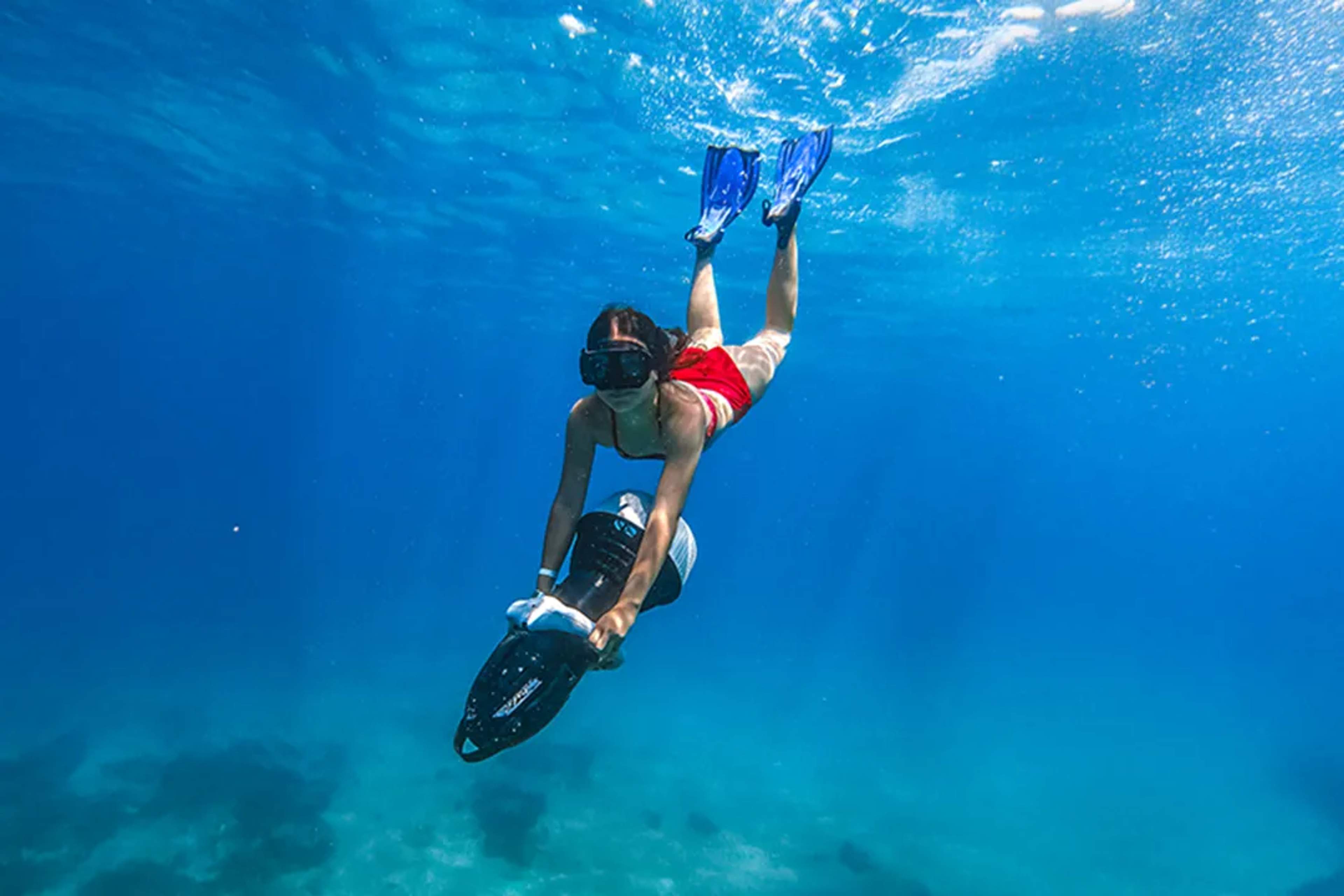 Snorkeler riding an underwater scooter in Los Cabos, exploring clear blue waters on a guided ocean adventure