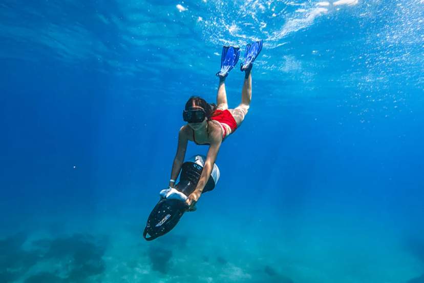 Snorkeler riding an underwater scooter in Los Cabos, exploring clear blue waters on a guided ocean adventure