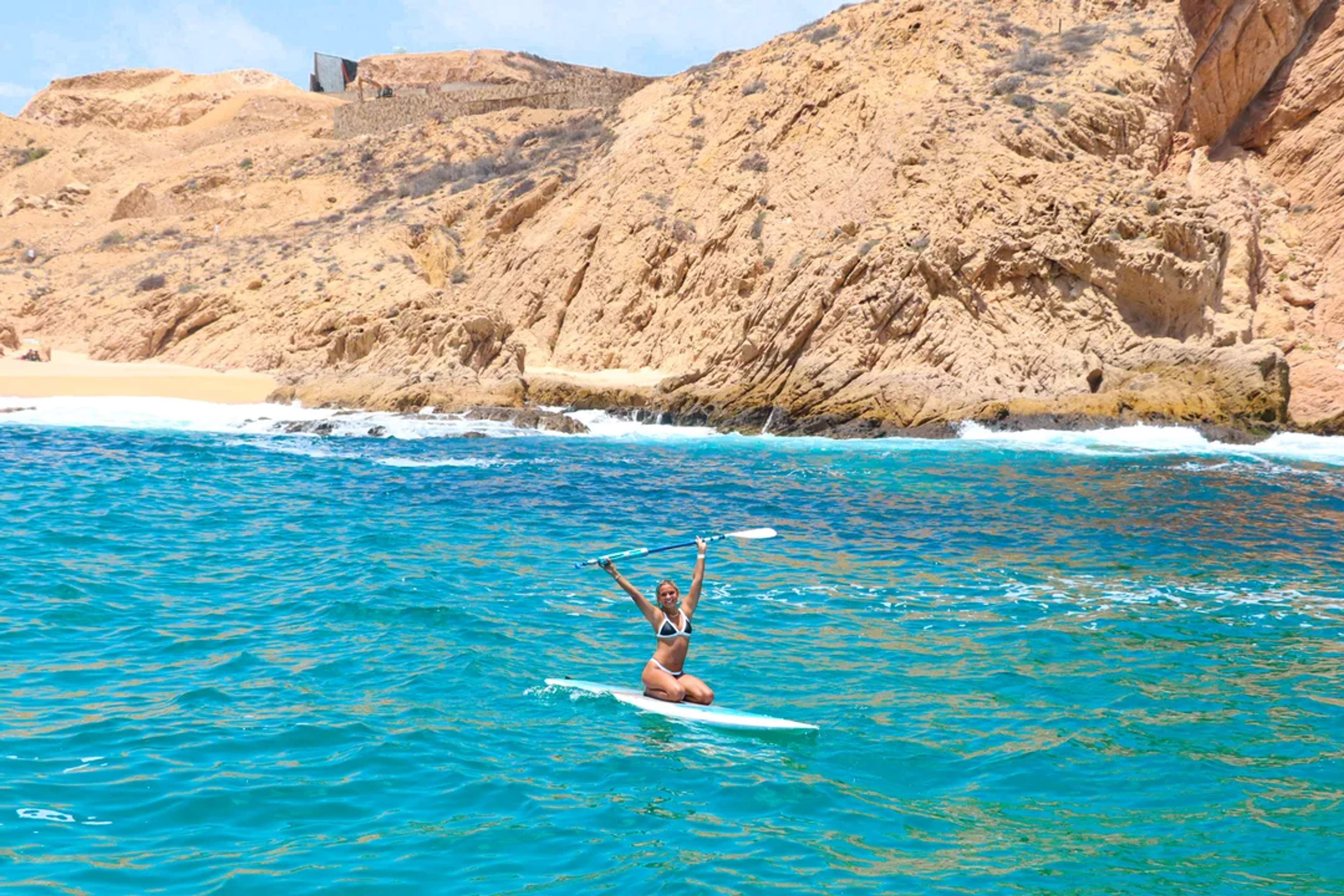 Disfruta de paddleboard en las aguas turquesas de Cabo, rodeado de acantilados dorados y playas.