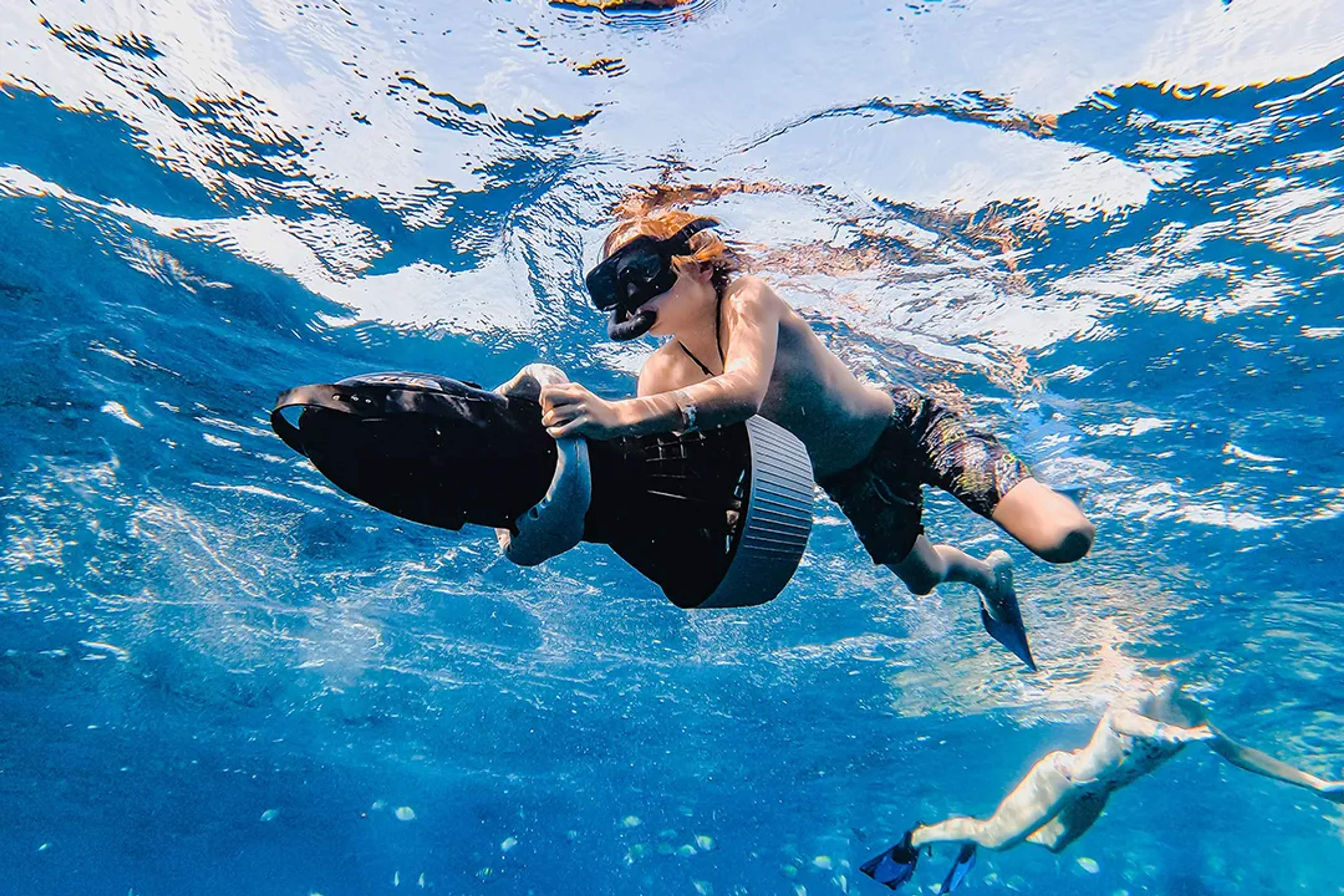 Joven haciendo snorkel con scooter submarino en un tour de aventura marina en Cabo San Lucas