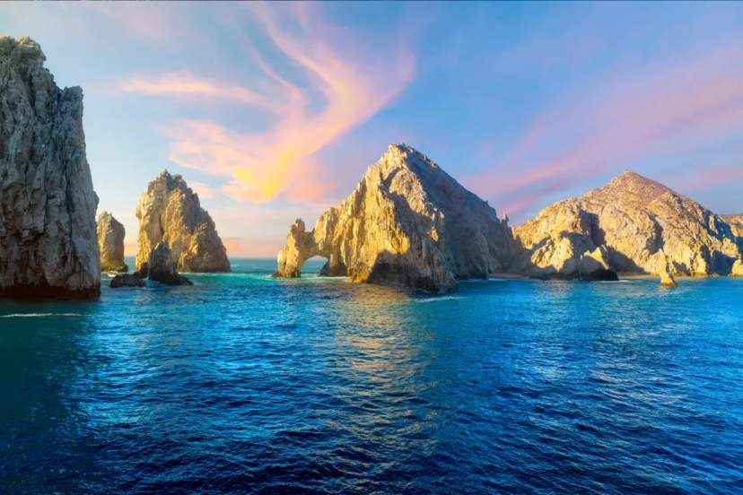 Las formaciones rocosas de El Arco se alzan dramáticamente desde aguas turquesas al amanecer en Cabo San Lucas.