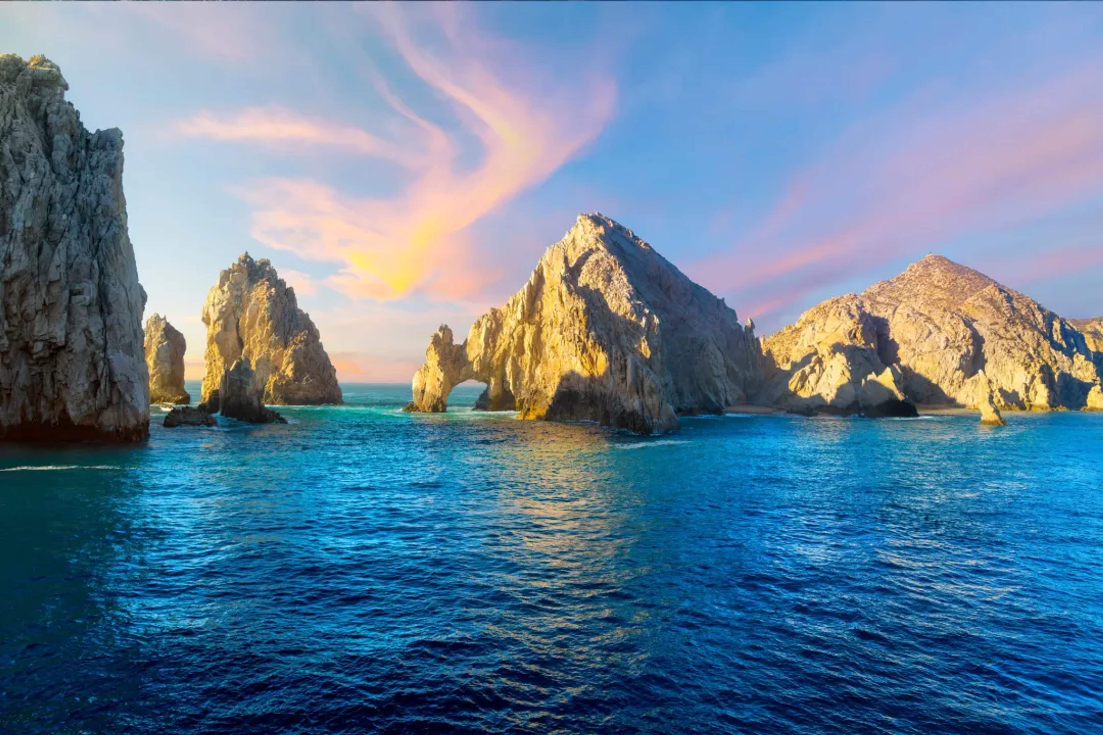 Las formaciones rocosas de El Arco se alzan dramáticamente desde aguas turquesas al amanecer en Cabo San Lucas.