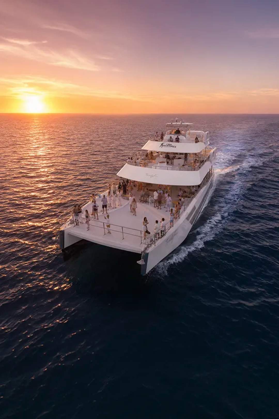 Guests dancing and having fun at a Cabo Party Boat at sunset.