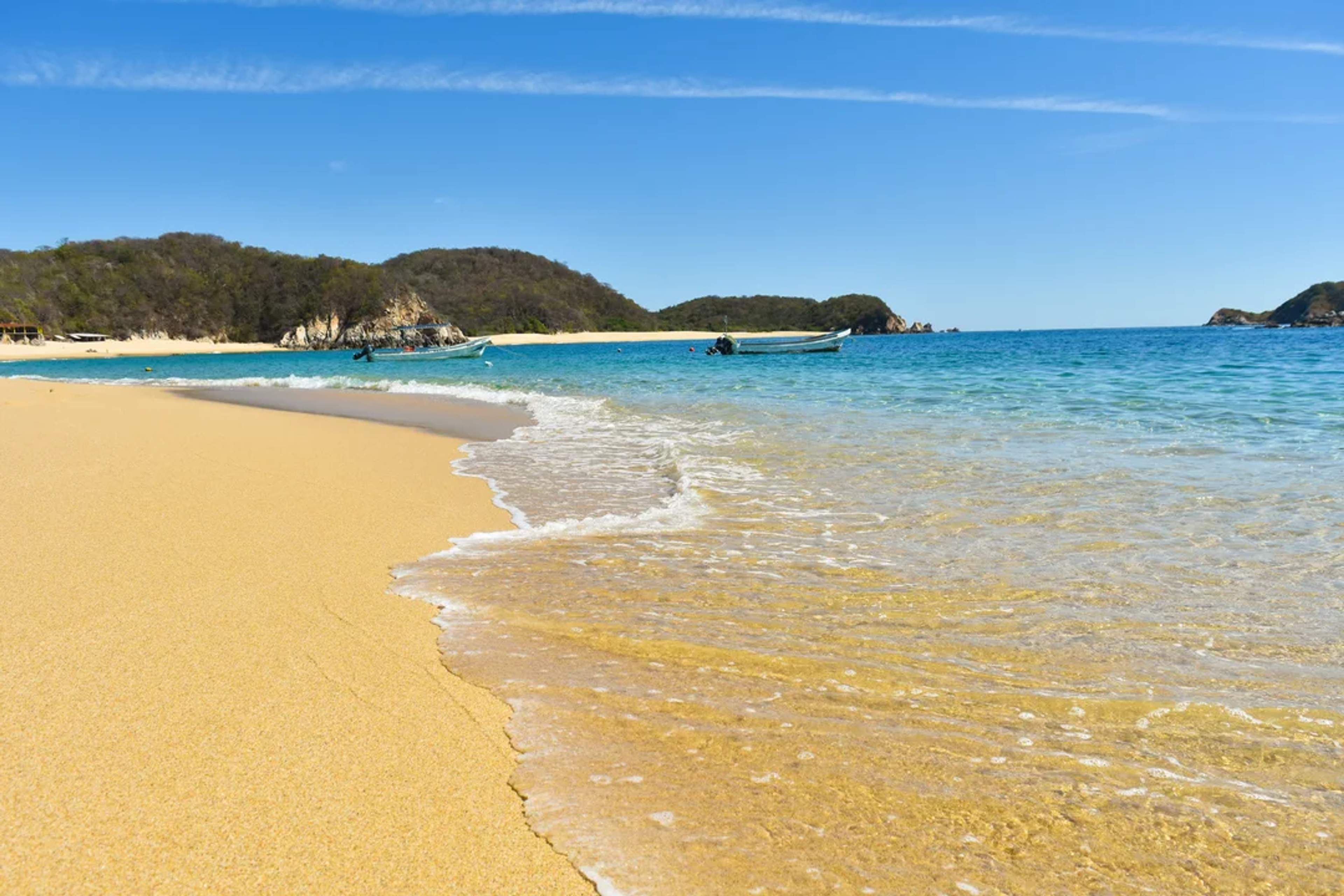 Playa virgen de arena dorada y mar cristalino, ideal para relajarse o explorar en lancha.