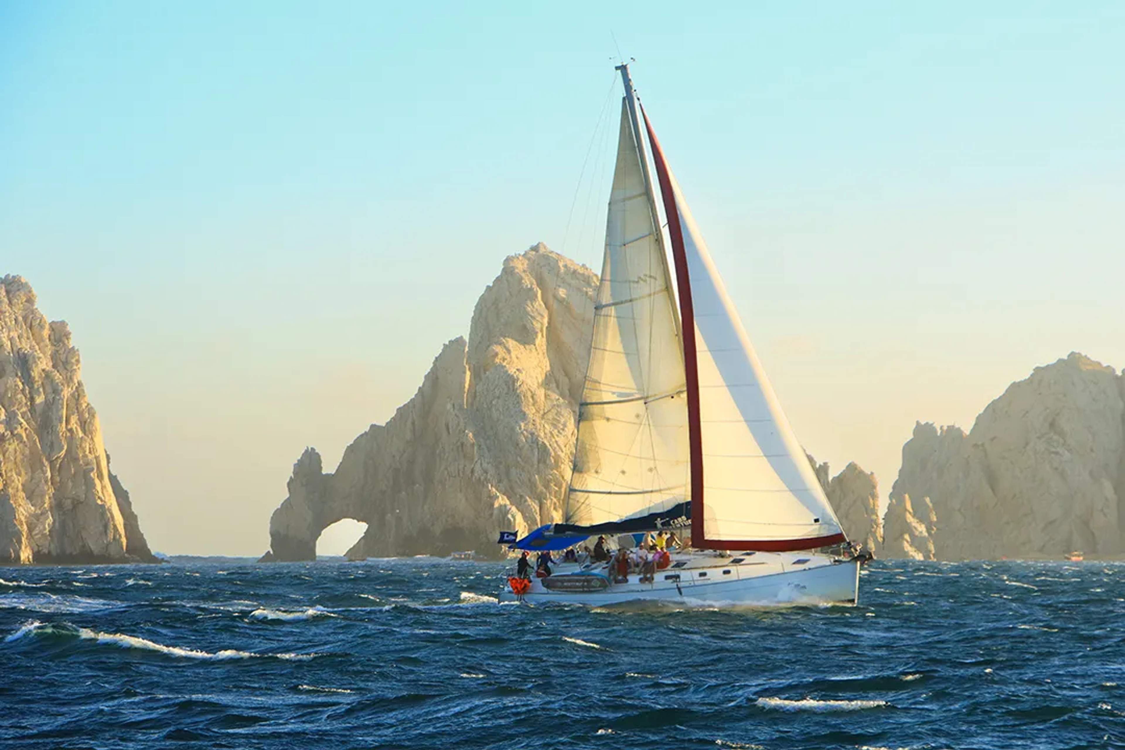 Tour de velero lujo frente al Arco de Cabo San Lucas al atardecer con vistas al mar y servicio premium a bordo