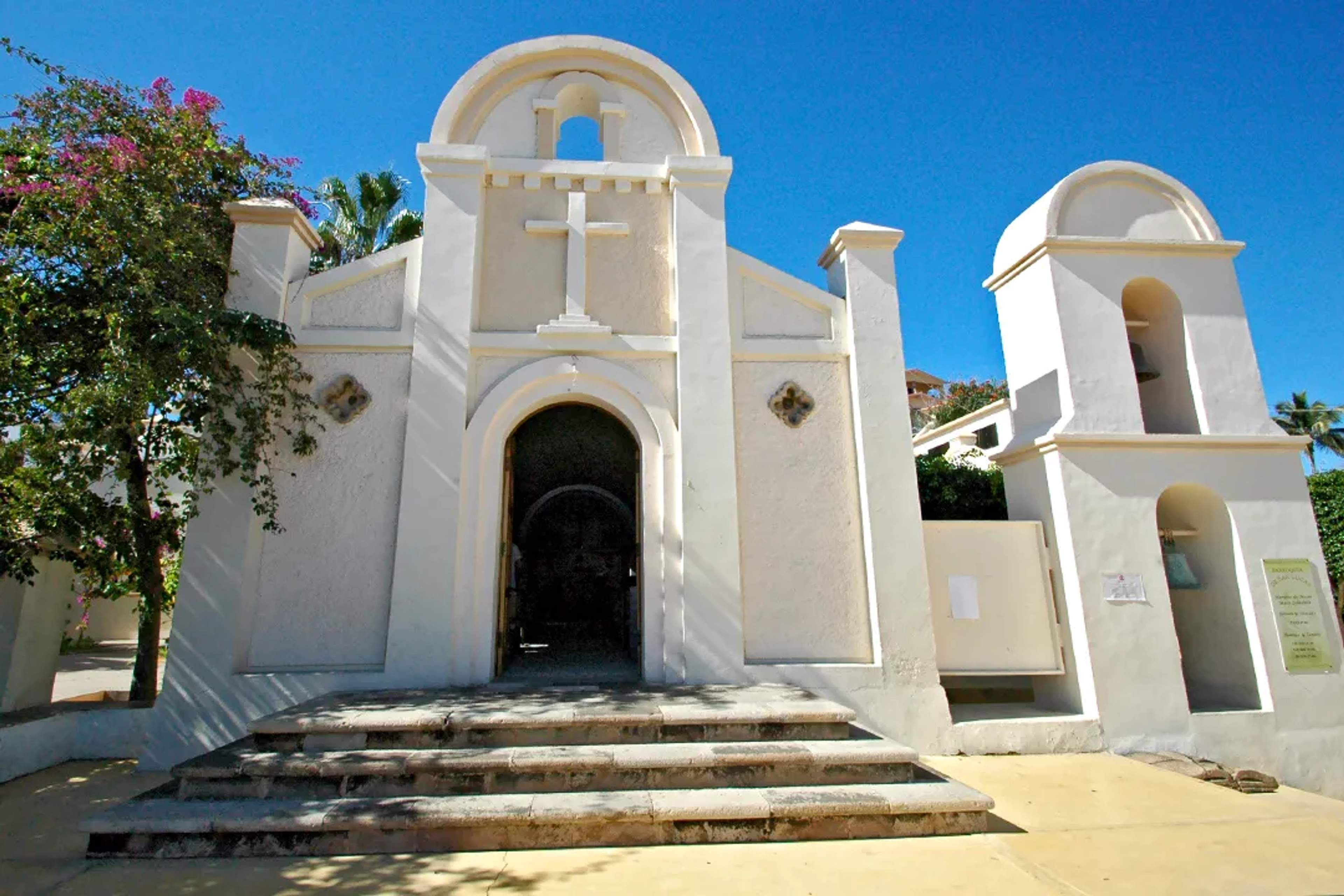 Historic white chapel in Cabo San Lucas with bell tower under clear blue sky