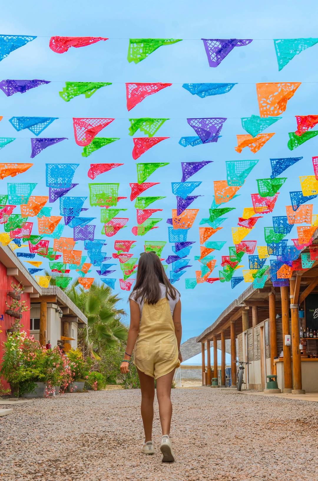 A UTV kicks up sand as it speeds along a beach with the ocean in the background, under a partly cloudy sky.