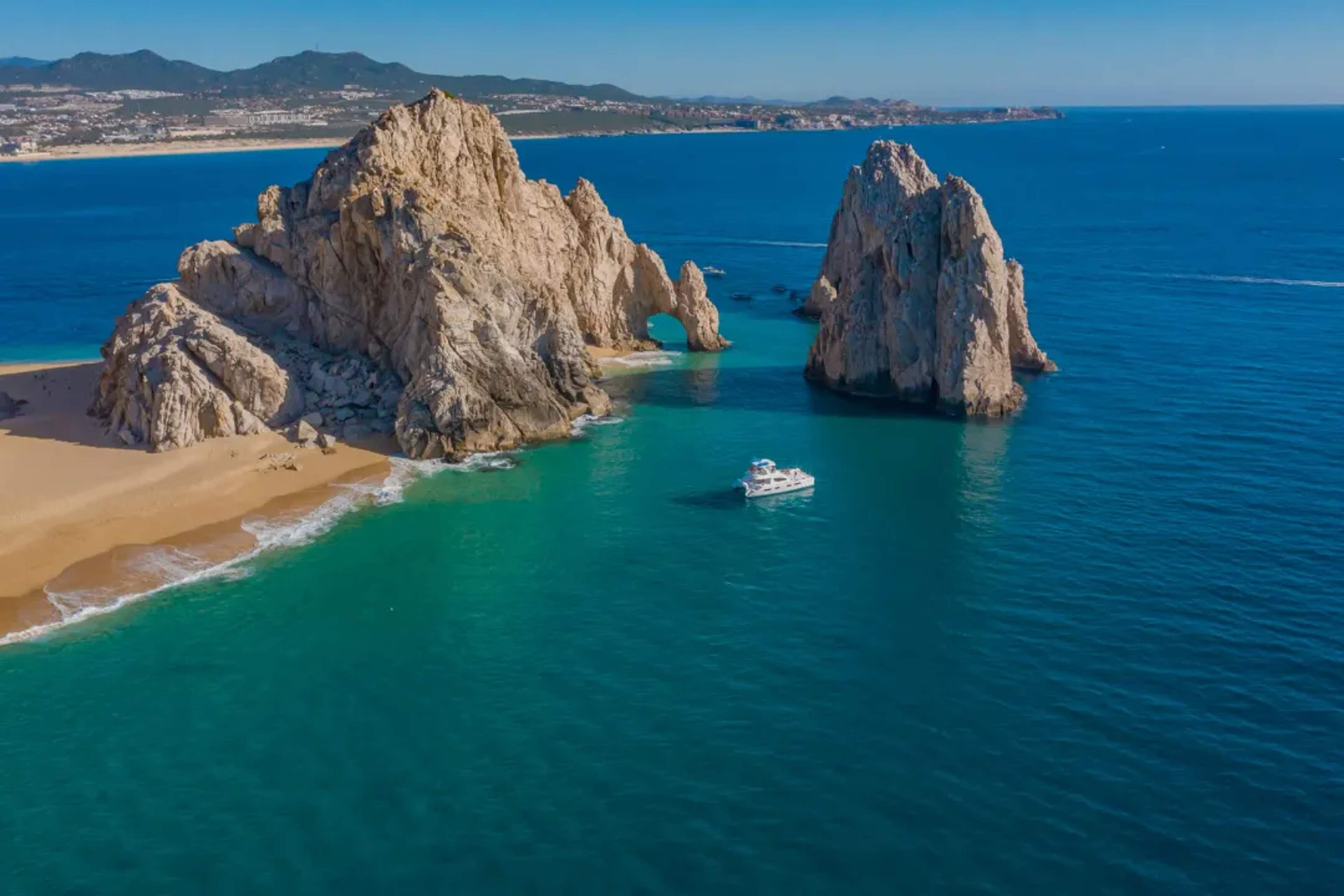 Vista aérea de un bote de snorkel anclado en una cala turquesa junto a formaciones rocosas dramáticas en el Corredor