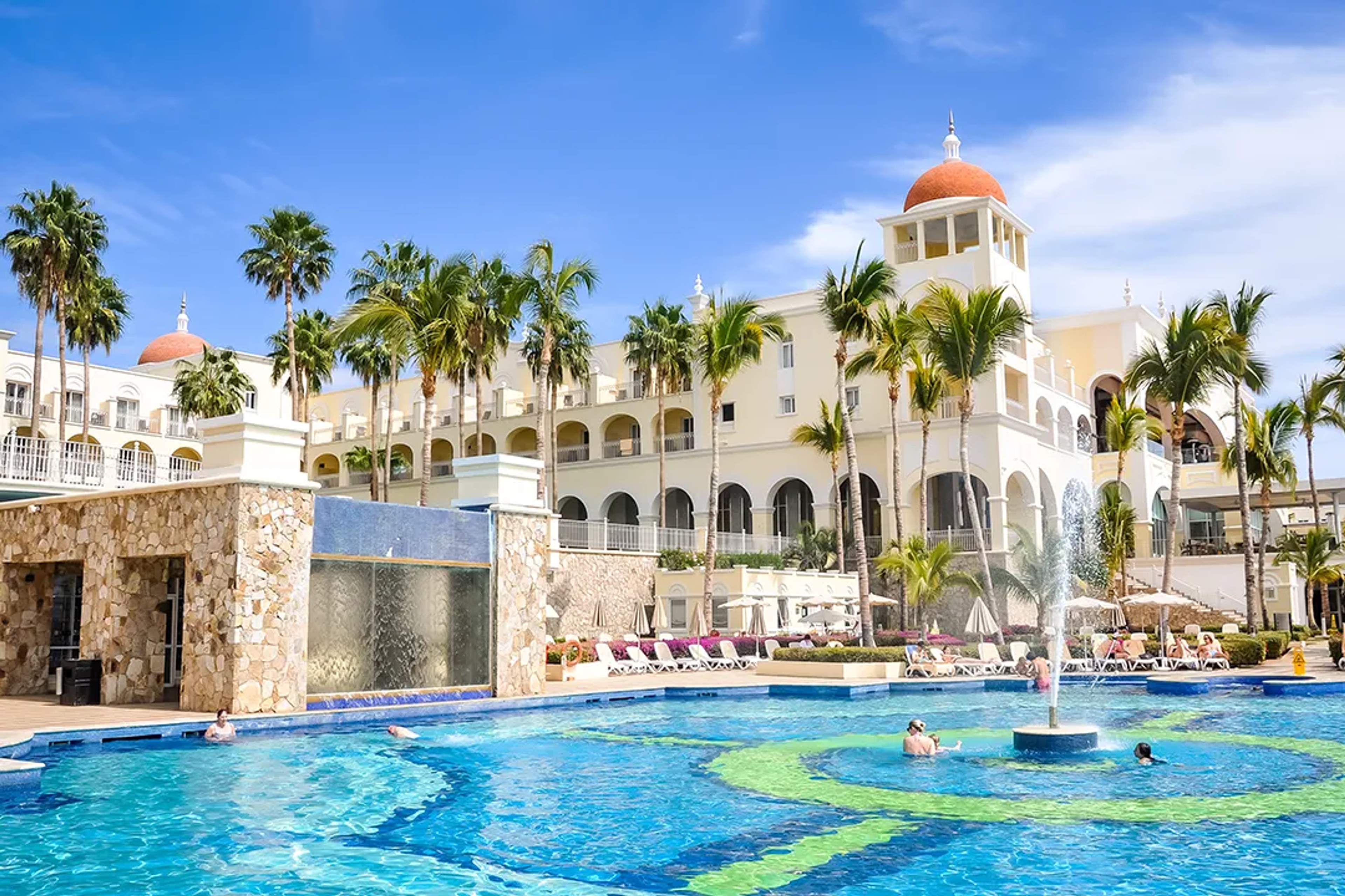 Luxury resort in Cabo San Lucas with pool, palm trees, and oceanfront setting for relaxing vacation stay