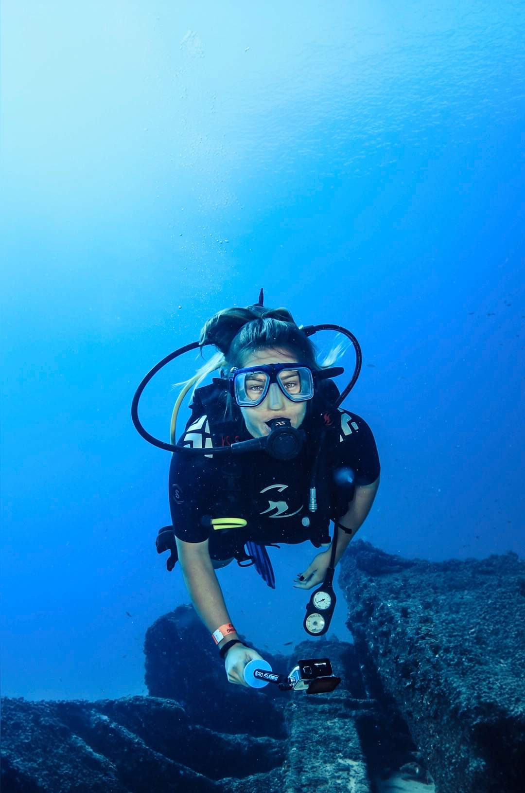 Diver with a camera in hand exploring an underwater shipwreck