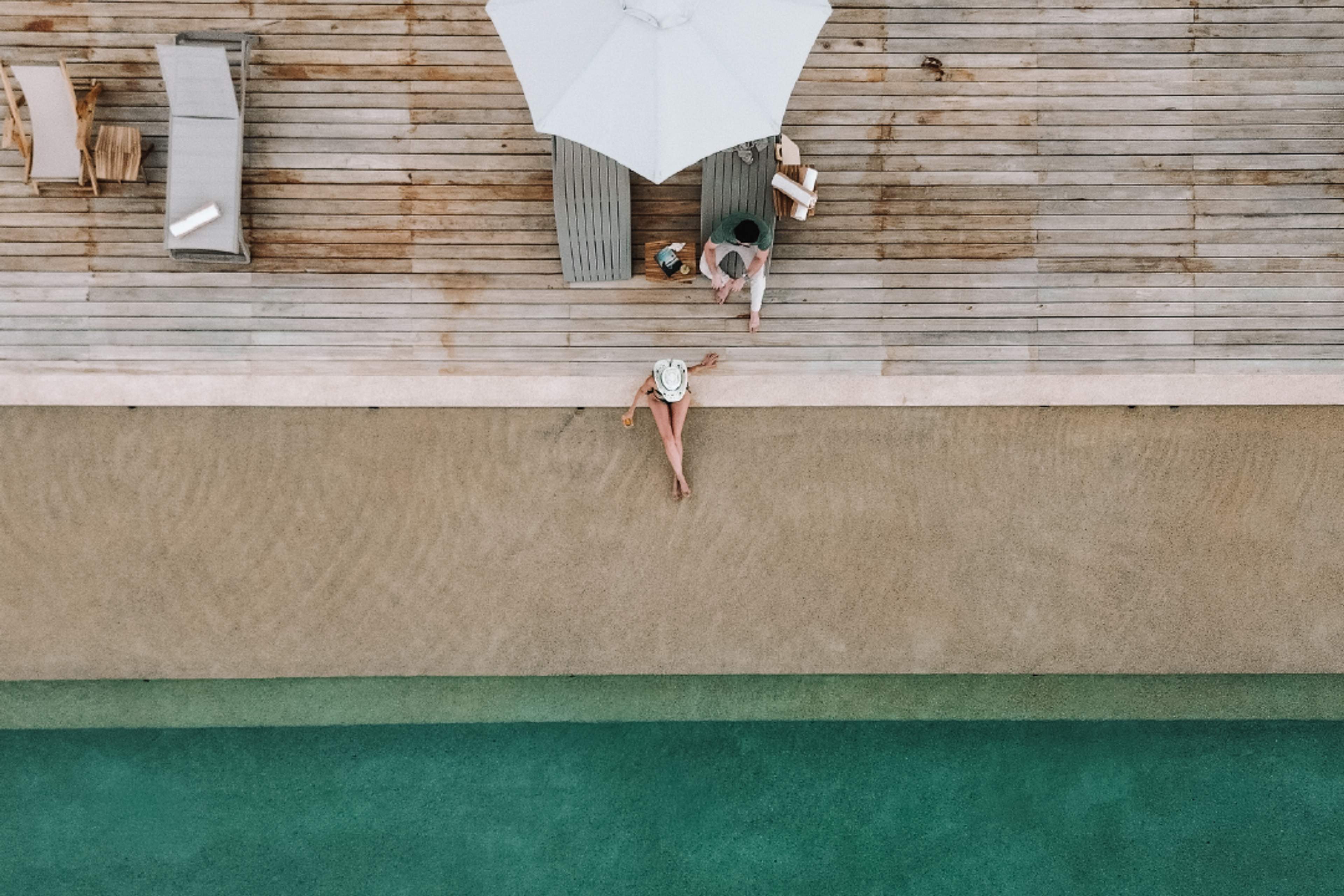 Aerial view of woman by infinity pool deck with loungers and umbrella at Tierra Sagrada Cabo