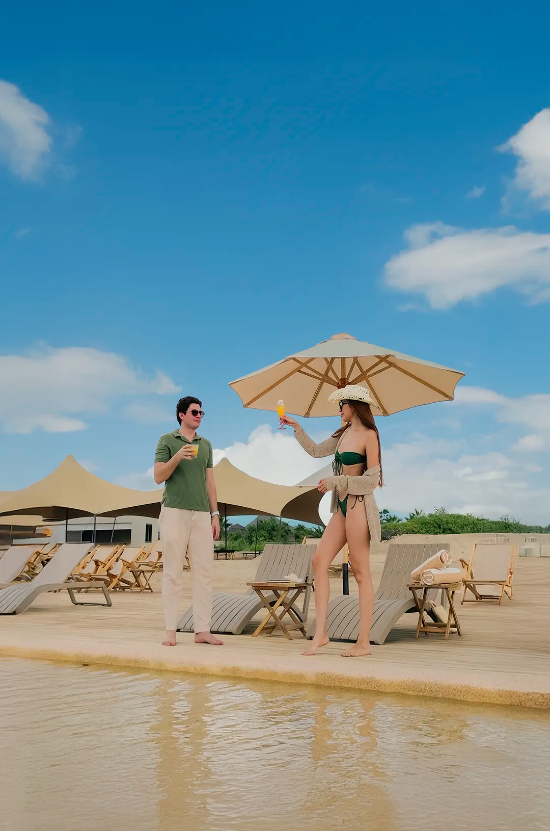 Couple toasting with cocktails by the pool at Tierra Sagrada Beach Club, Los Cabos, Mexico.