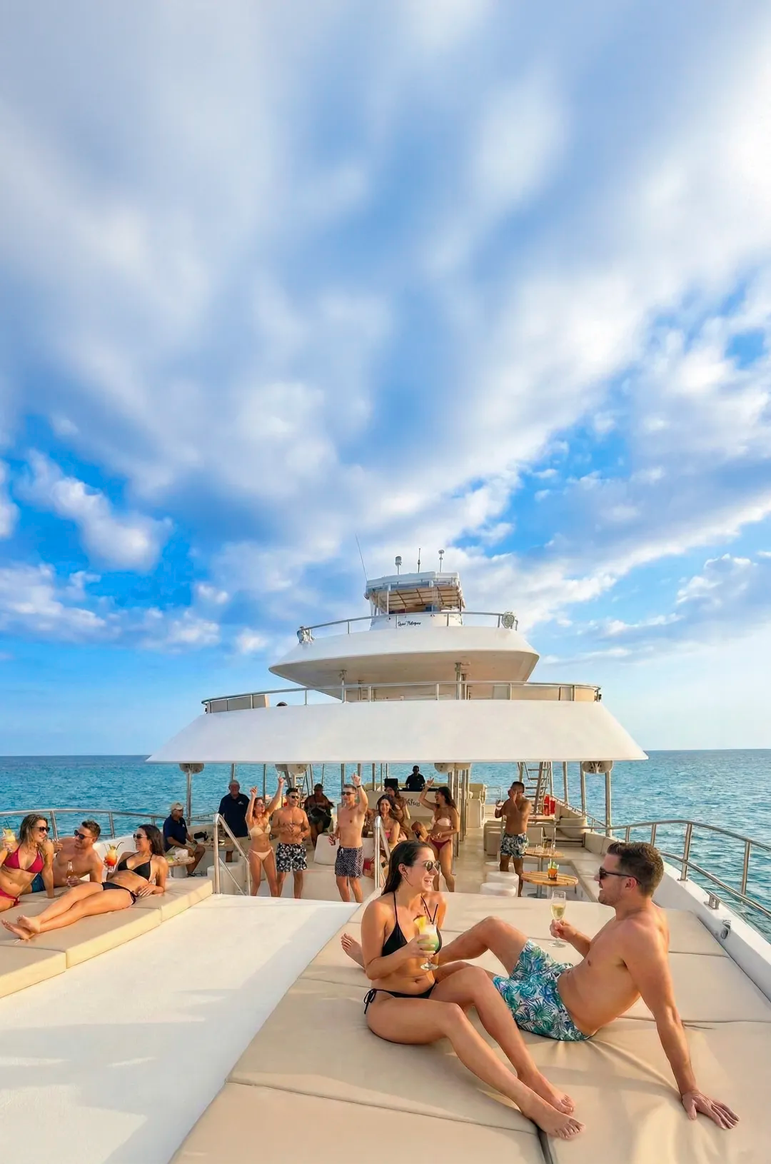 Guests relaxing on spacious sun decks aboard the TwentyFive premium catamaran, enjoying drinks and ocean views in Cabo.