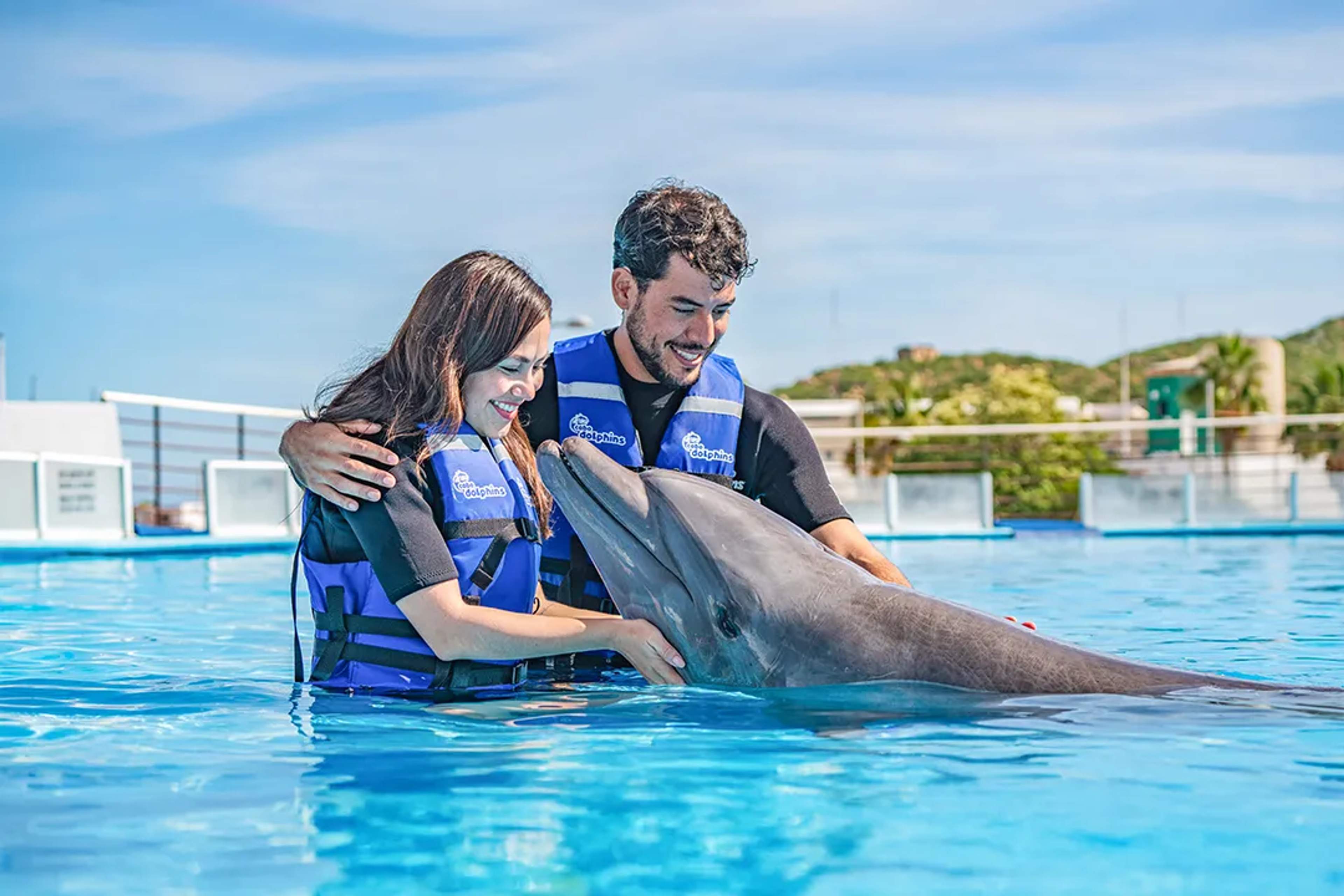 Couple enjoying a guided dolphin swim experience, interacting up close with a dolphin at a marine park