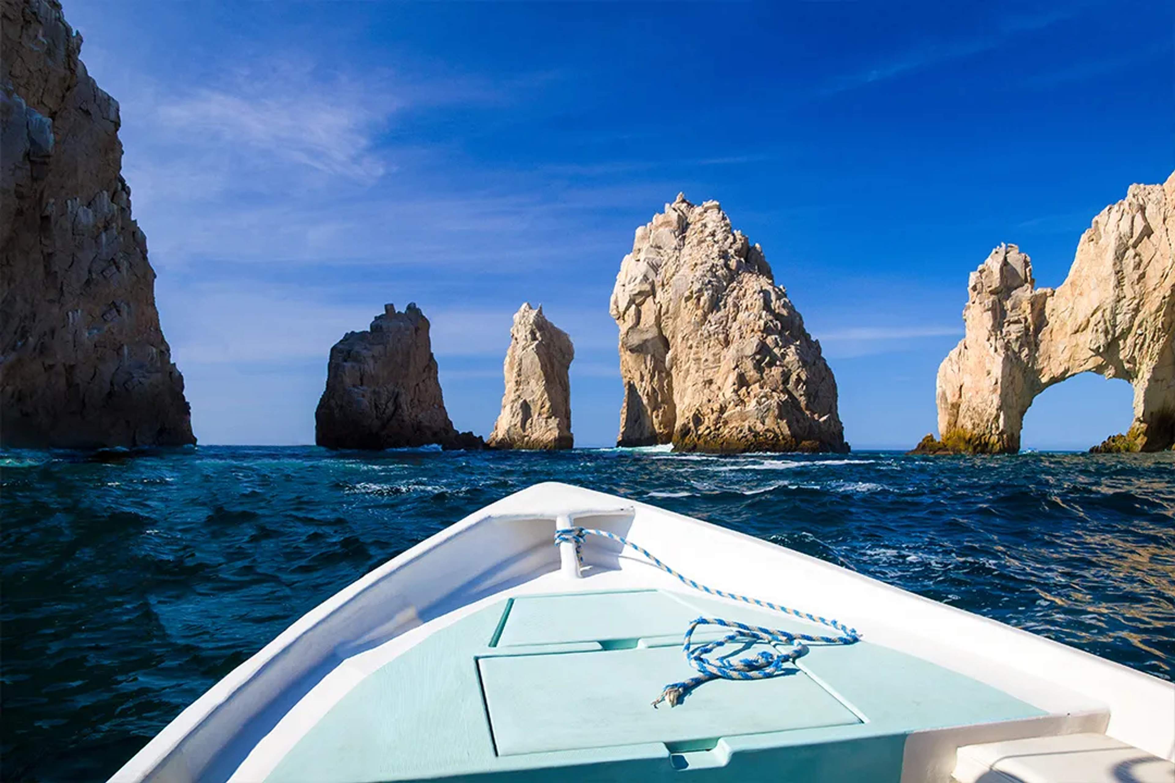 Boat approaching El Arco rock formations in Los Cabos, a must-see landmark on scenic ocean and sightseeing tours