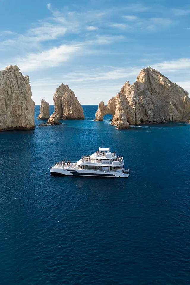 TwentyFive premium 100-ft catamaran sailing in Cabo San Lucas, triple-deck design, open sea views and luxury day cruise.