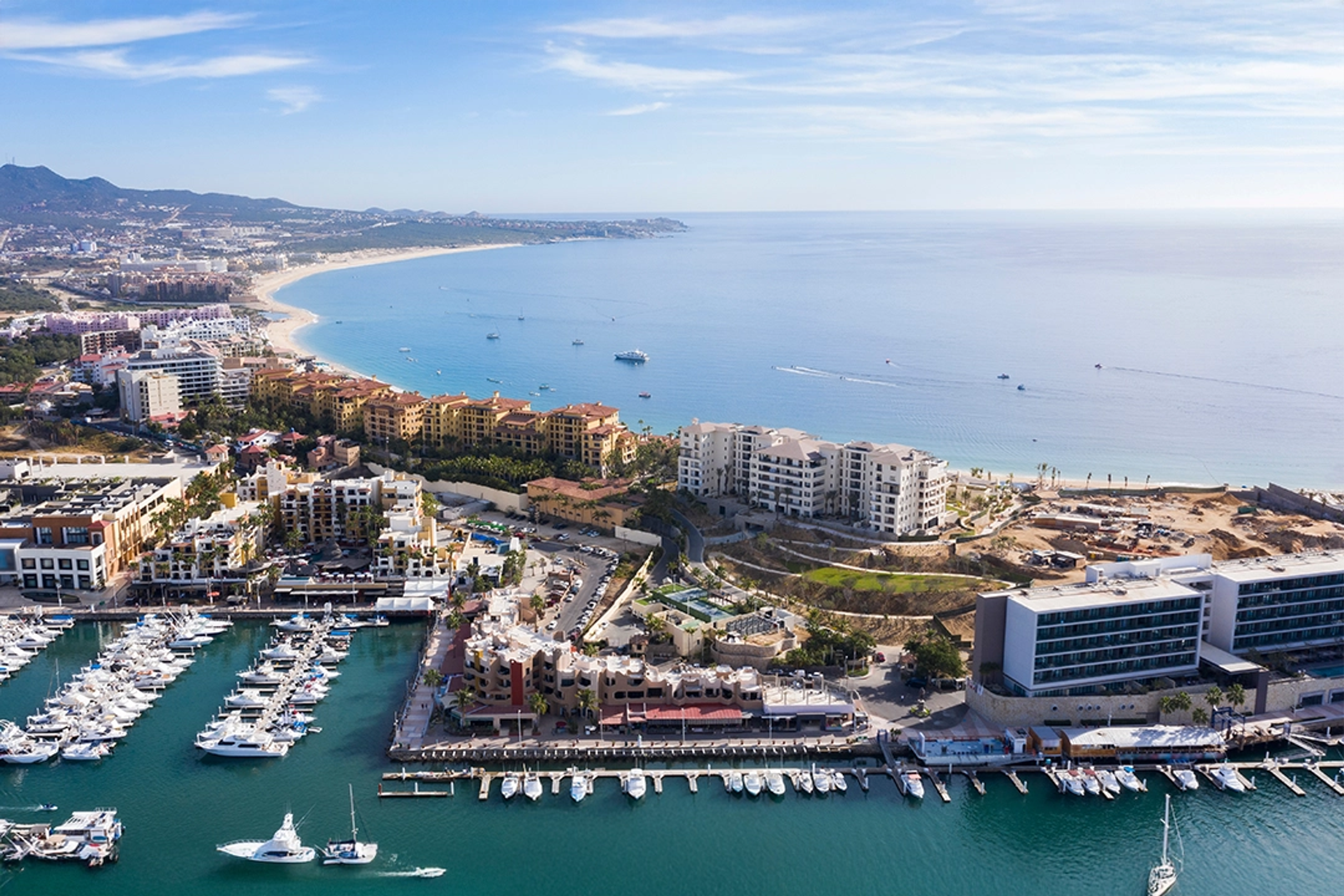 Impresionante vista aérea de Cabo San Lucas, destacando la marina, hoteles de lujo y la hermosa costa.