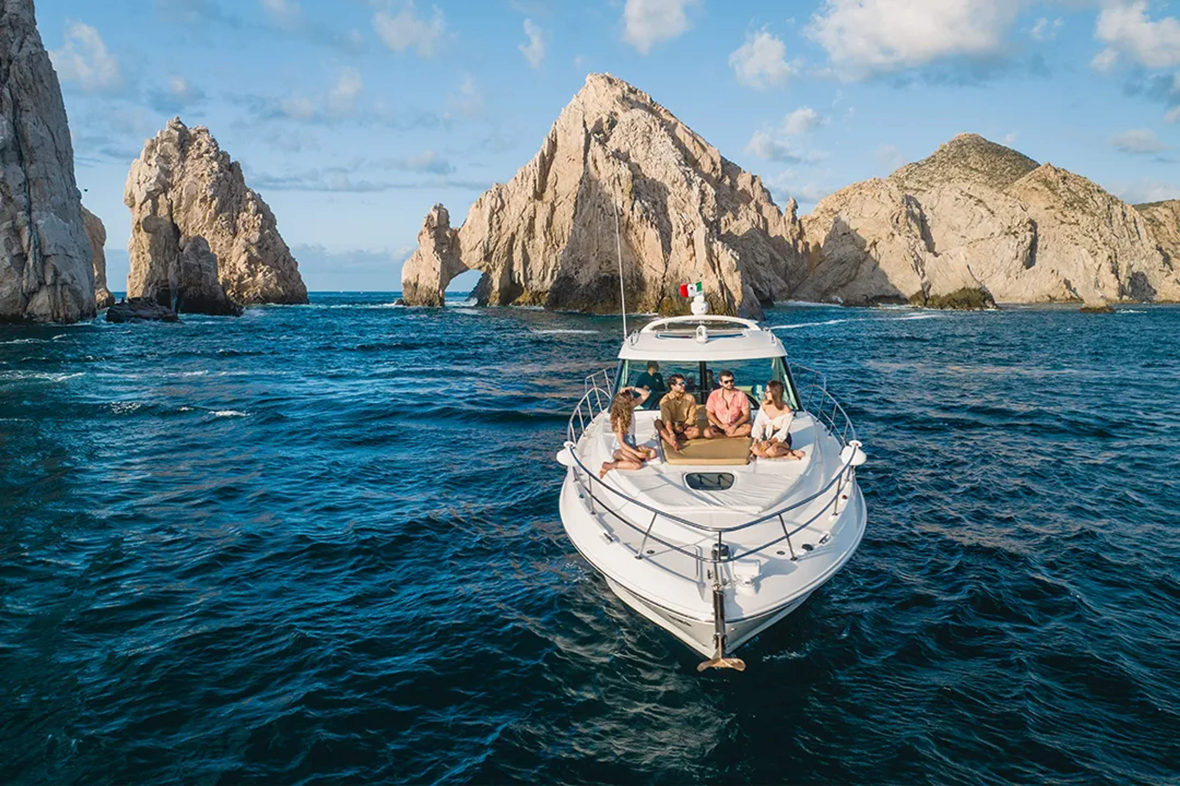 Luxury private yacht cruising near El Arco in Los Cabos, Mexico, with friends enjoying ocean views and iconic rock formations