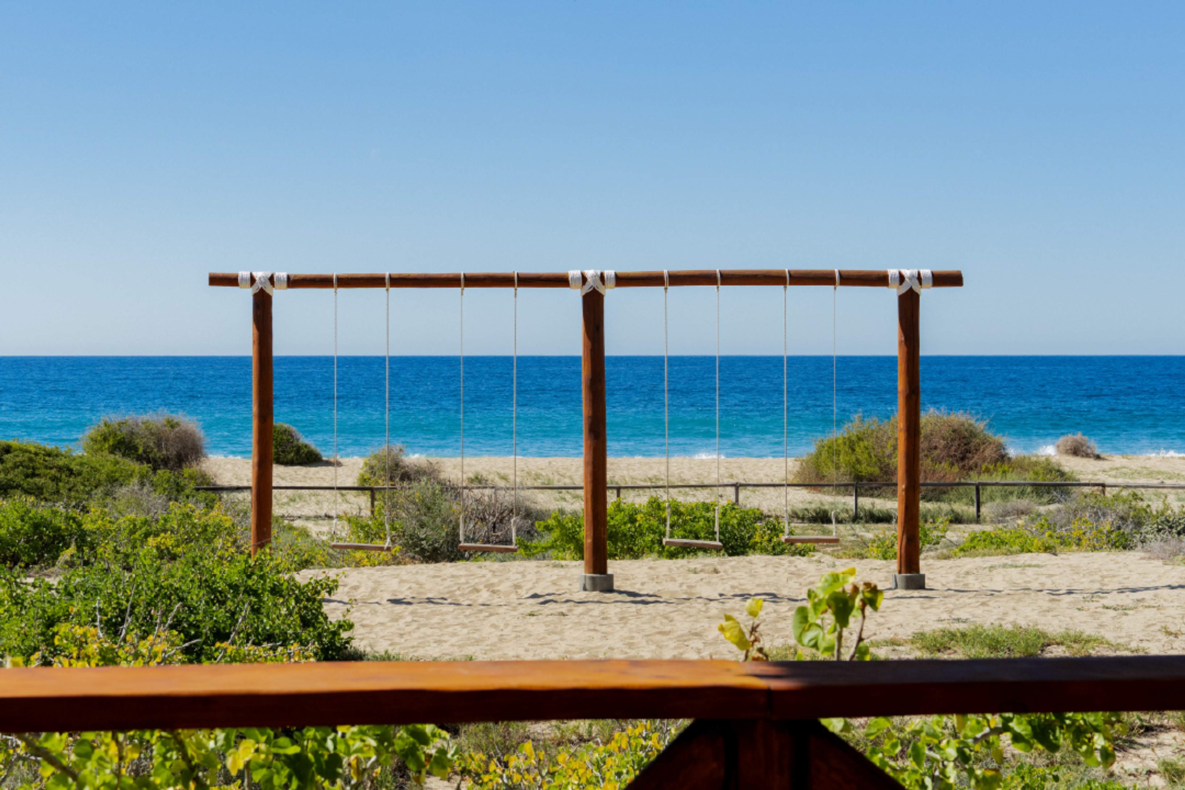 Wooden beach swings facing turquoise ocean at Tierra Sagrada, Instagram spot in Cabo San Lucas