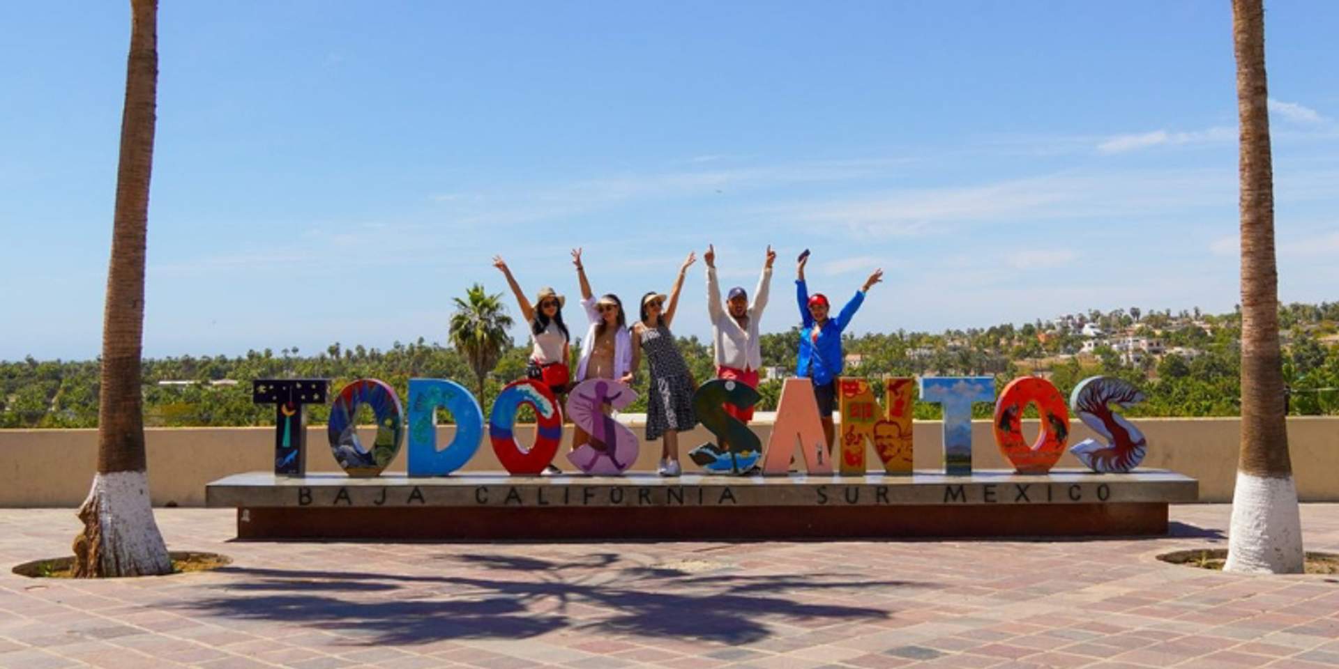 Tourists posing at colorful Todos Santos sign in Baja California Sur, near Cabo San Lucas