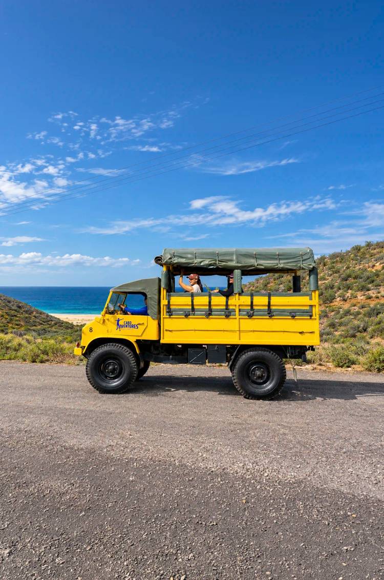 Guests aboard a yellow truck with ocean views on Pacific Zipline Adventure by Cabo Adventures.