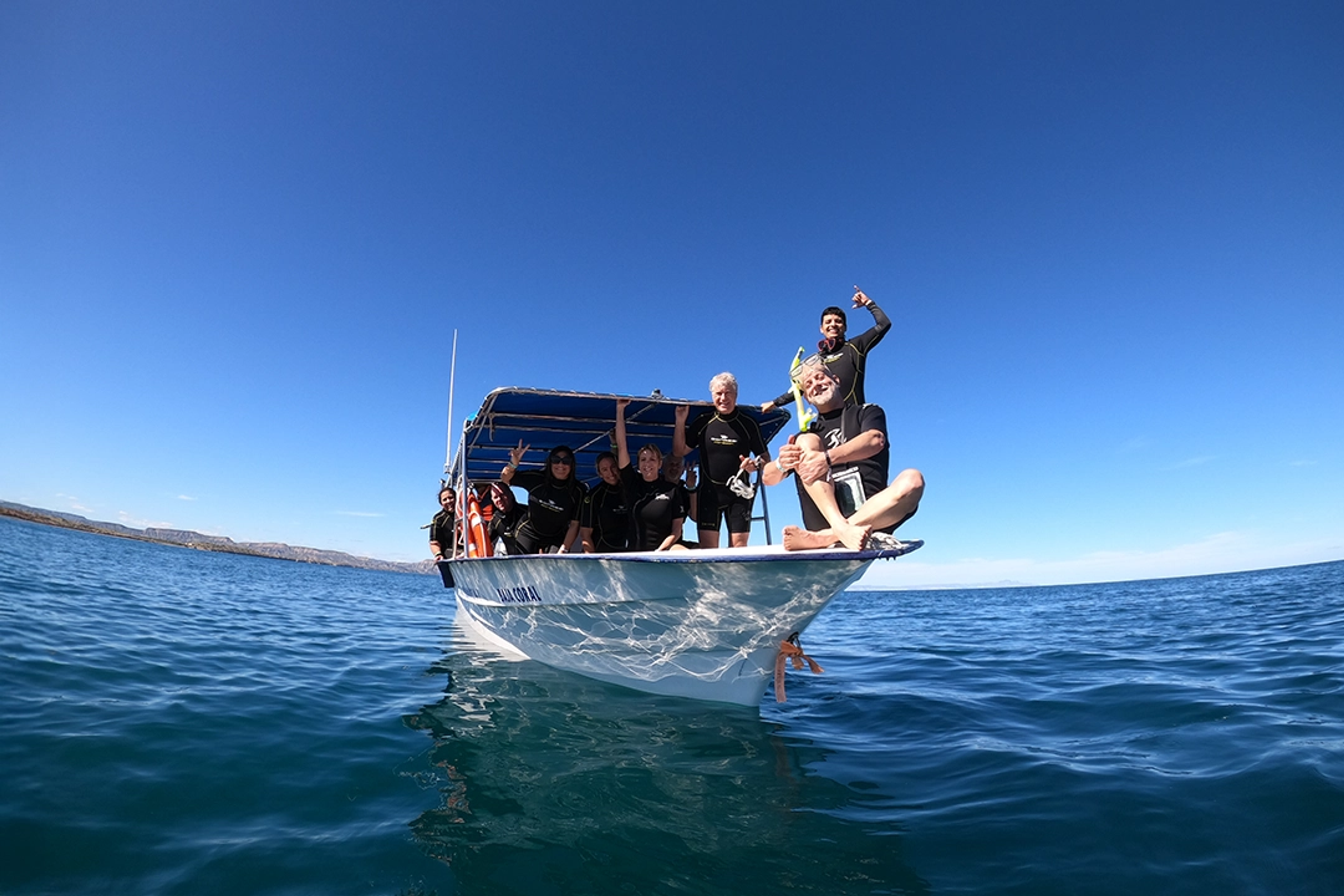 Un grupo de snorkelistas en un bote listos para una aventura oceánica bajo un cielo azul claro en Cabo.
