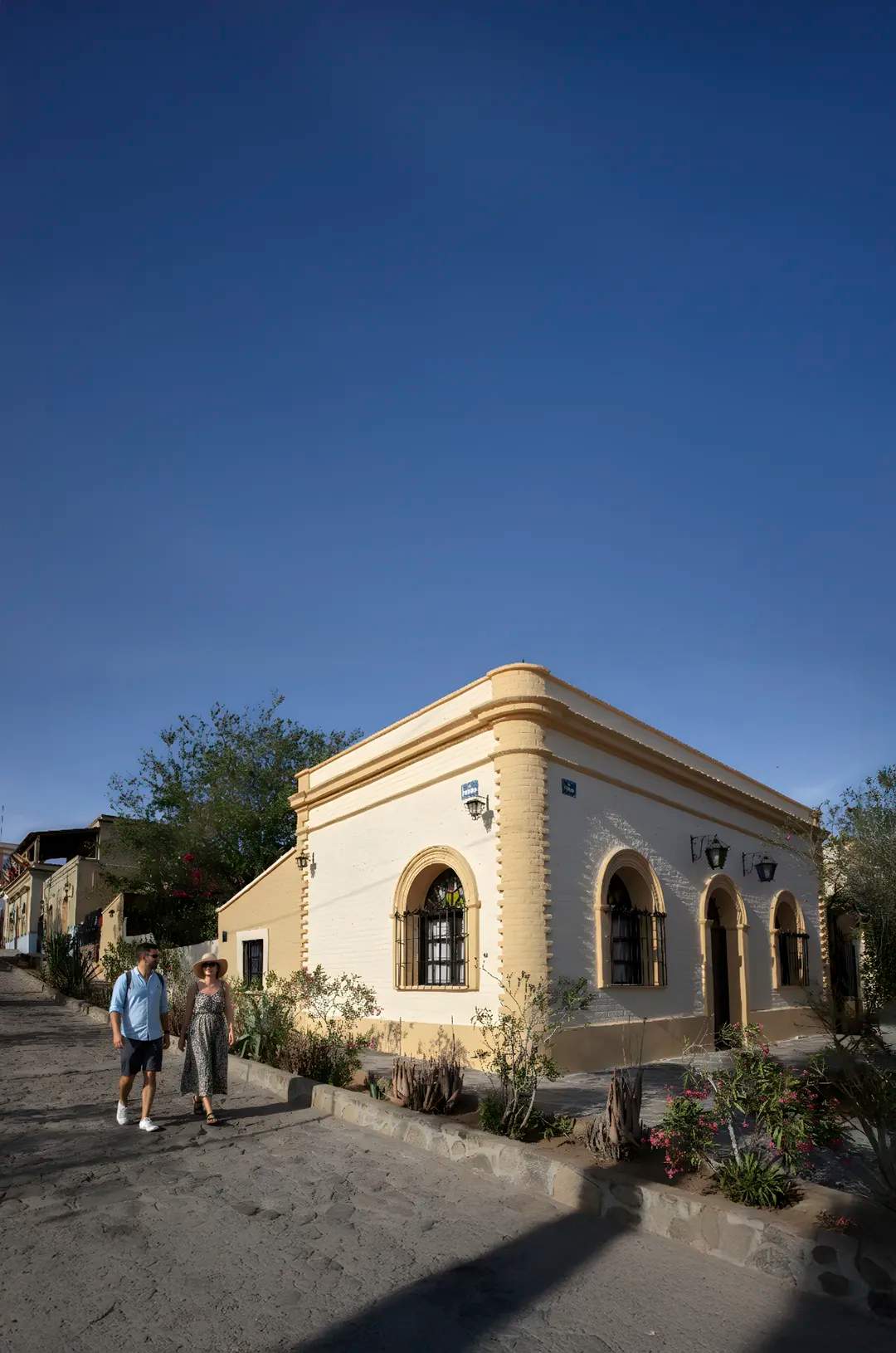 Visitors walking along cobblestone streets in El Triunfo, Baja California Sur, admiring restored historic buildings.