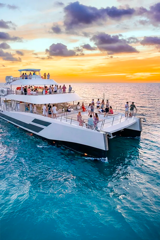 Guests dancing and having fun at a Cabo Party Boat at sunset.