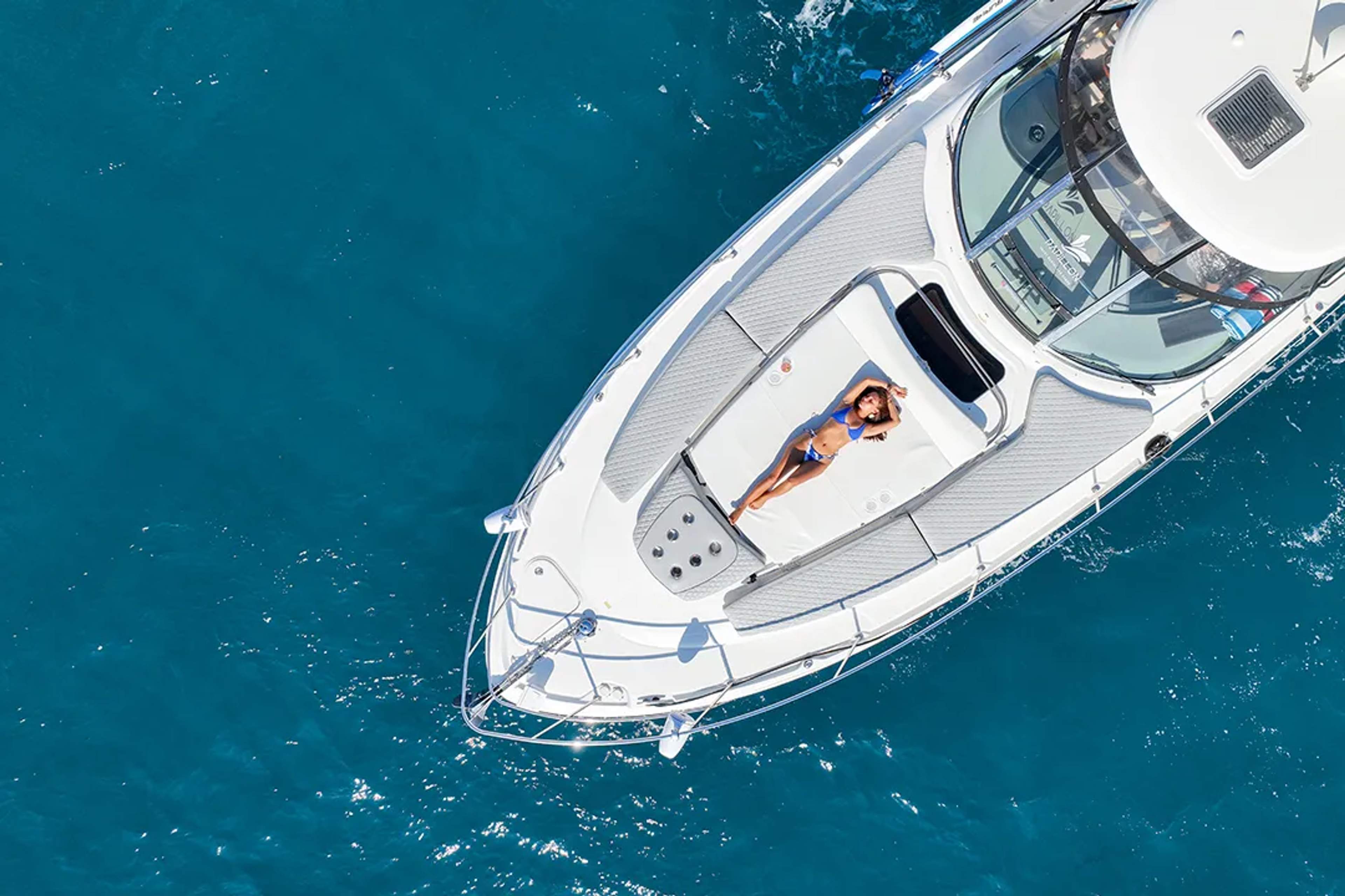 Aerial view of a woman sunbathing on a luxury yacht in Los Cabos, surrounded by crystal-clear ocean waters