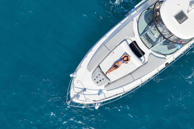 Aerial view of a woman sunbathing on a luxury yacht in Los Cabos, surrounded by crystal-clear ocean waters