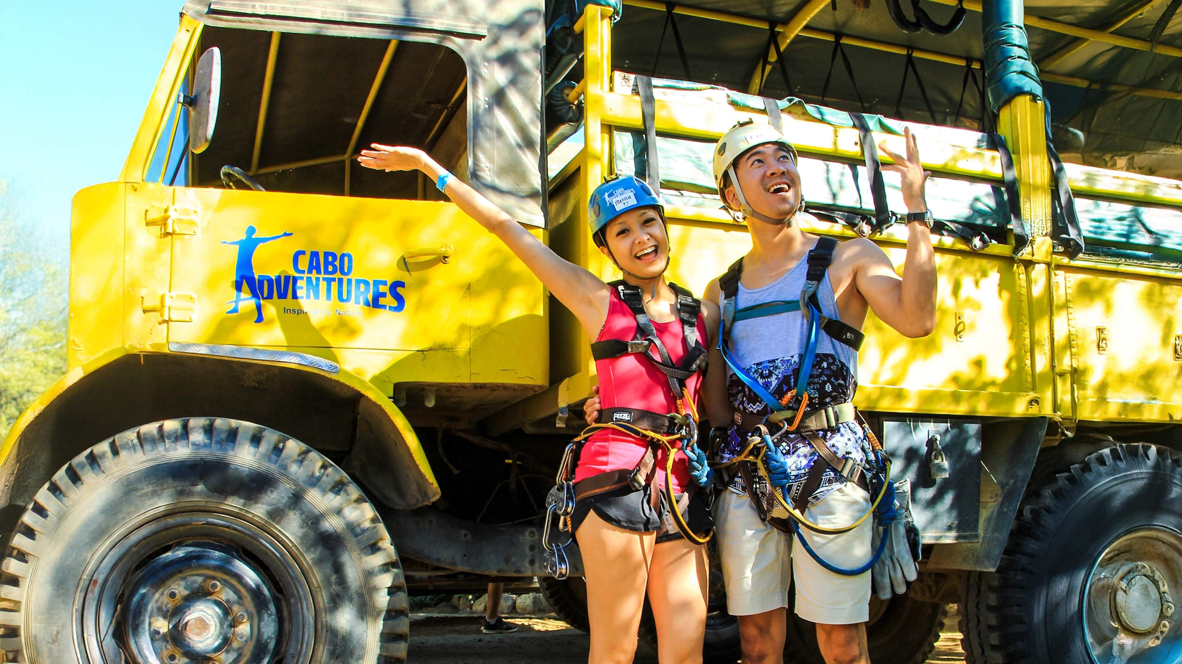 Excited adventurers pose by a Cabo Adventures truck, ready for a thrilling outdoor experience.