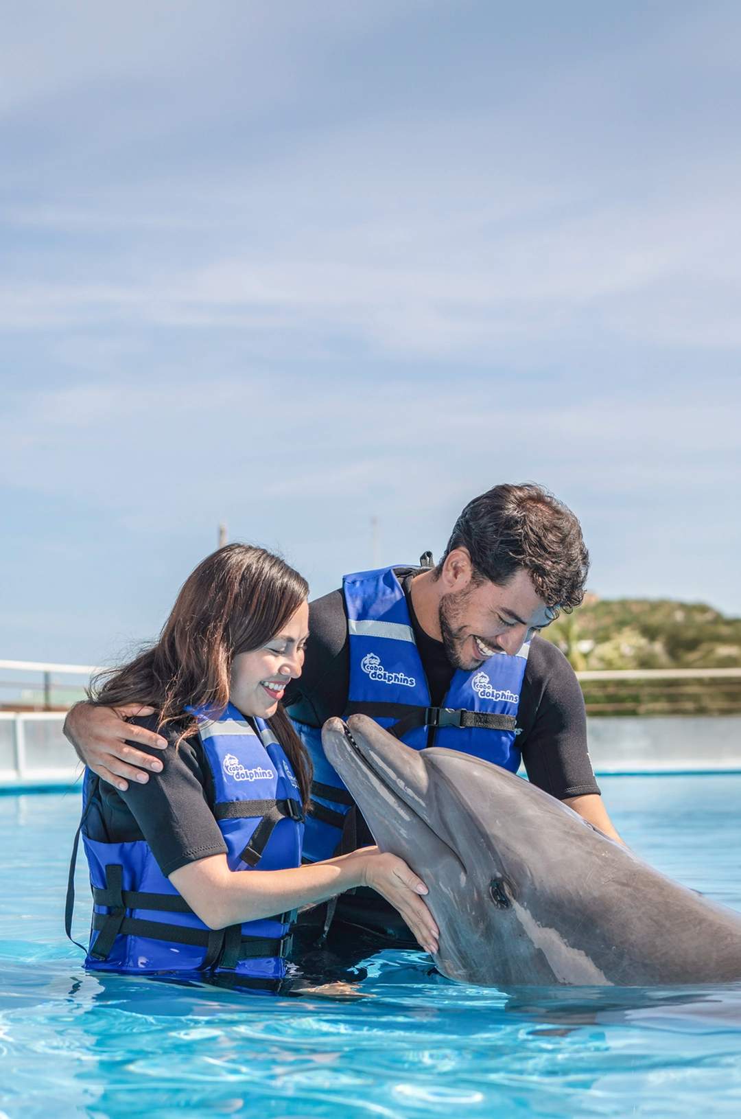 Couple enjoying a dolphin swim experience in Cabo San Lucas.