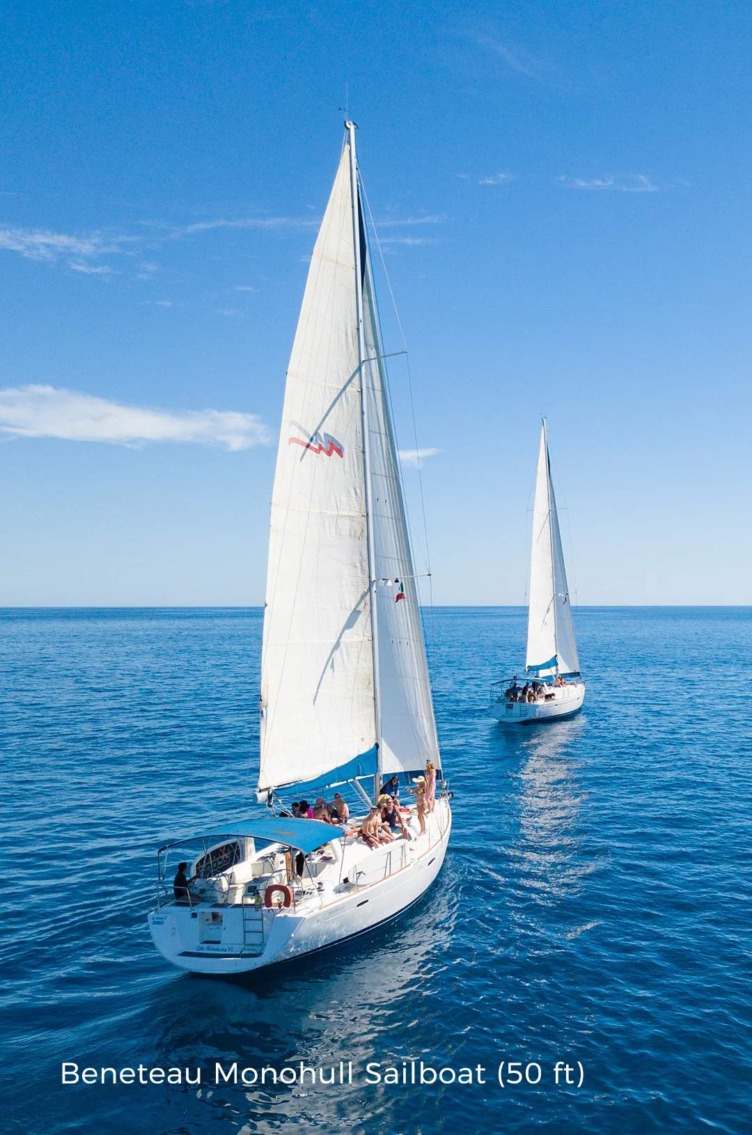 Two sailboats gliding side by side on calm blue waters under a clear sky.