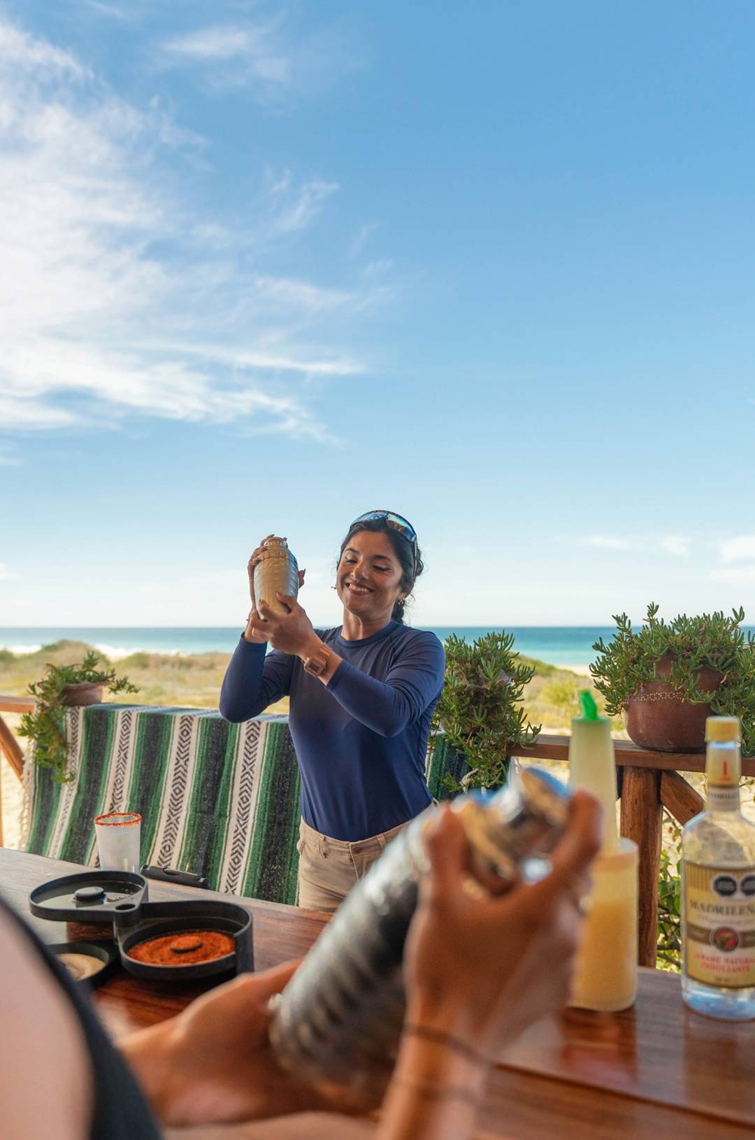 Electric bike tour in Cabo, woman making drinks at a beachside bar after a ride.