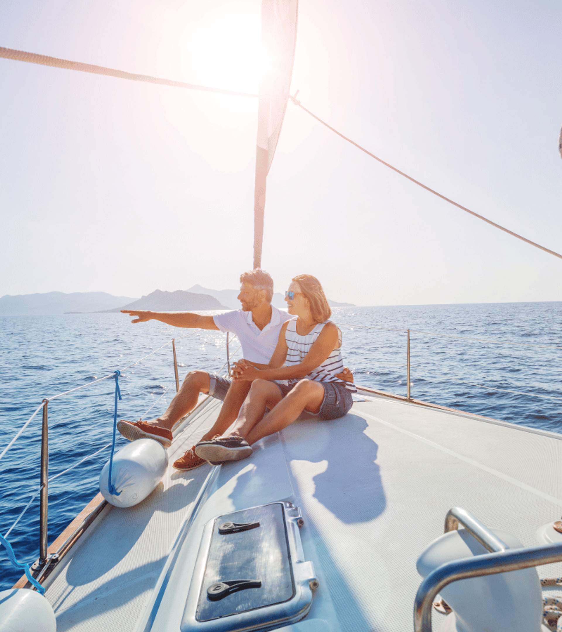 Couple sitting on a sailboat enjoying a sunny day on the ocean, pointing towards the horizon.