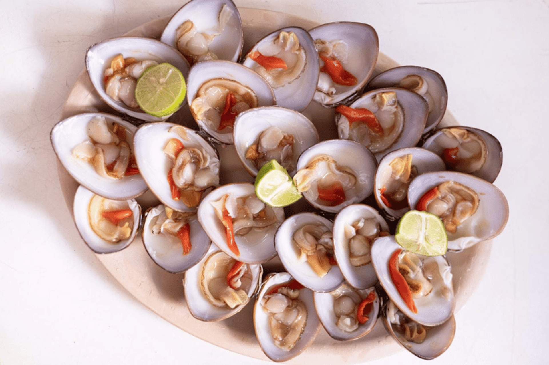  Plate of fresh clams garnished with lime and red pepper slices.