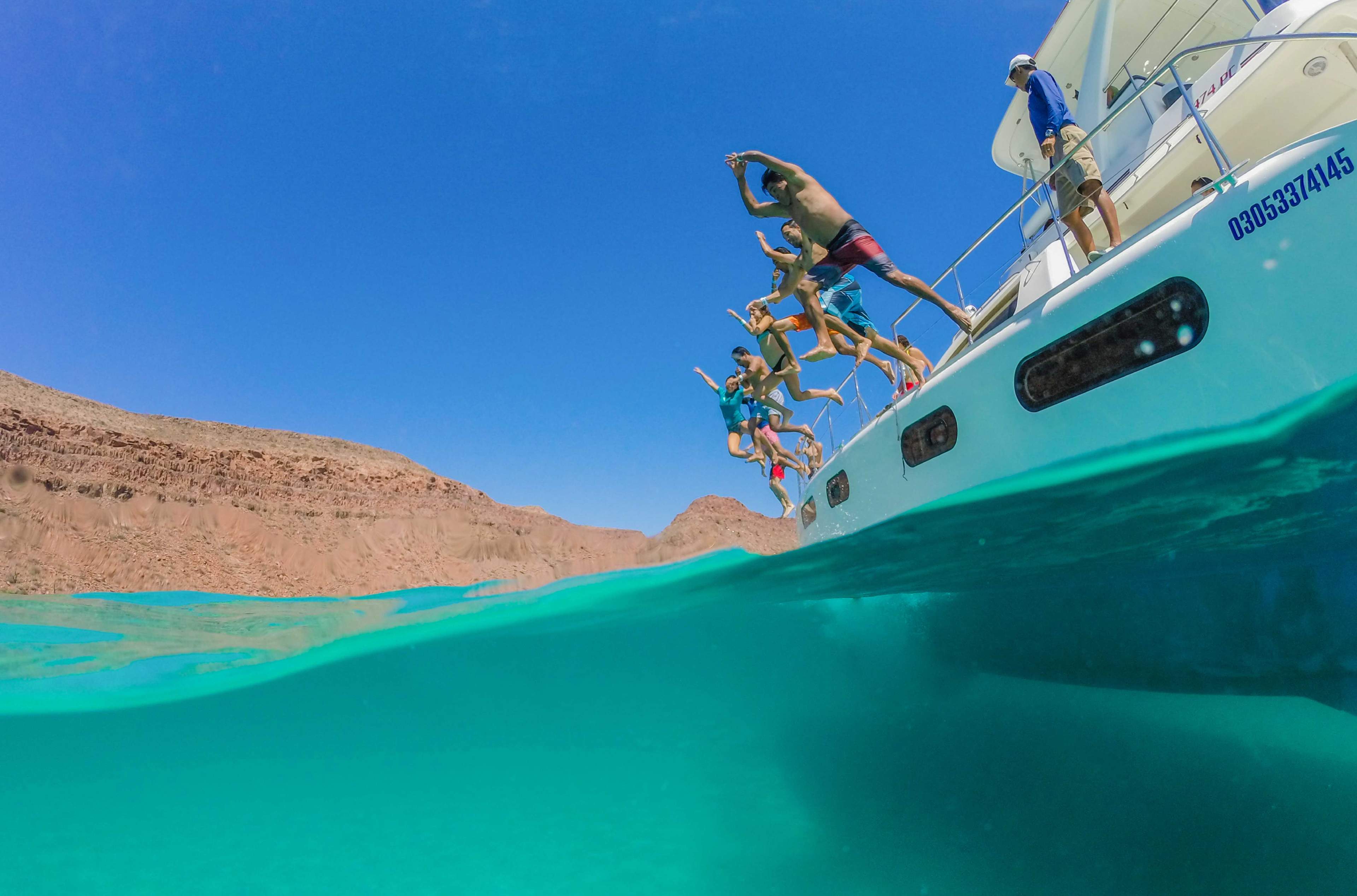 Persons jumping out of a boat to the water
