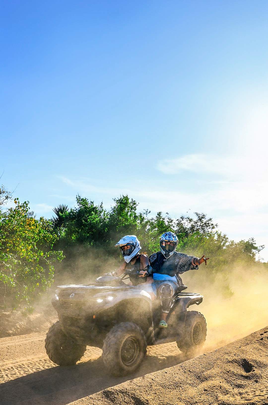 Couple on a off-road vehicle driving on a dusty road surrounded by cacti in the desert