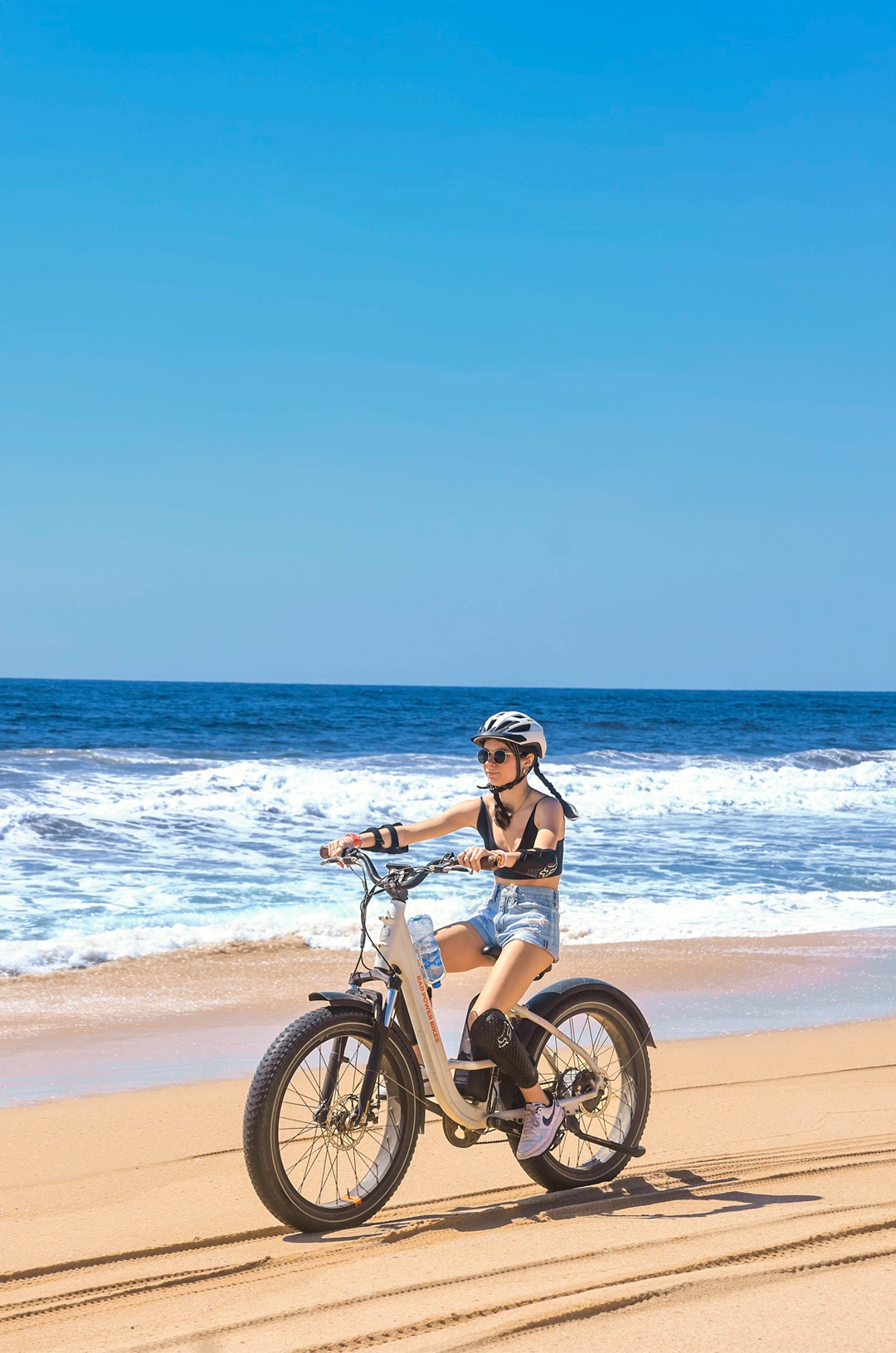 Cyclist enjoying an electric bike ride along the beach by the ocean.
