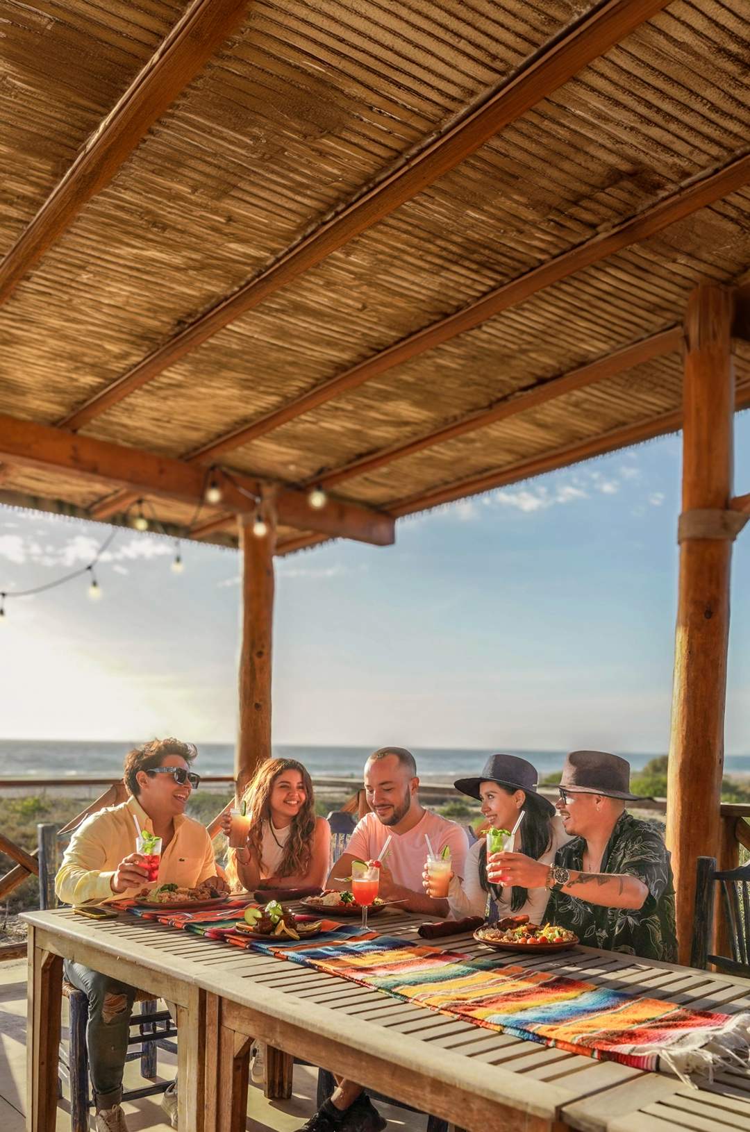Group of friends enjoying a meal and drinks on a terrace with an ocean view