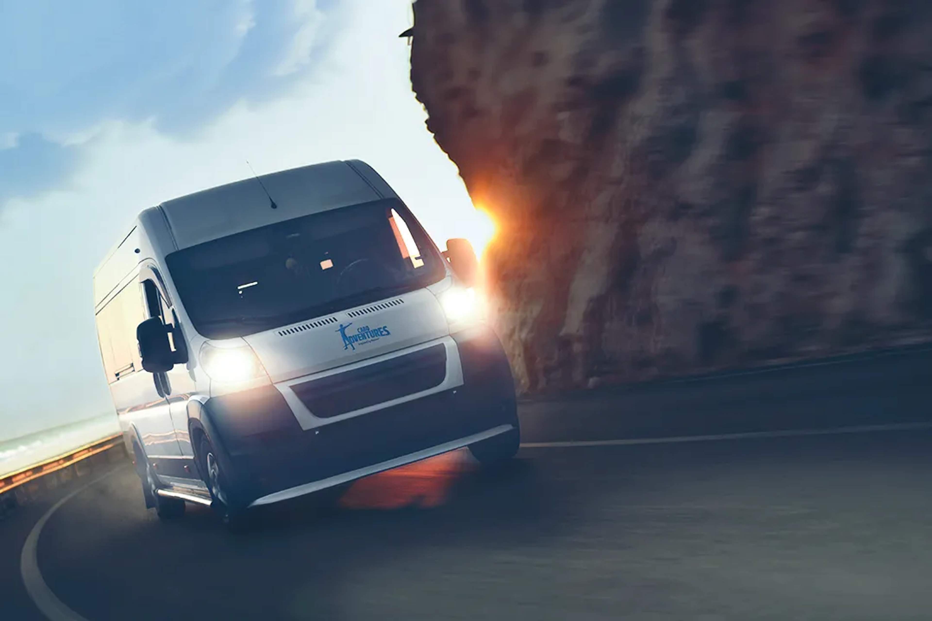  Cabo Adventures van driving along a coastal road at sunset, offering safe and comfortable transportation for tours.