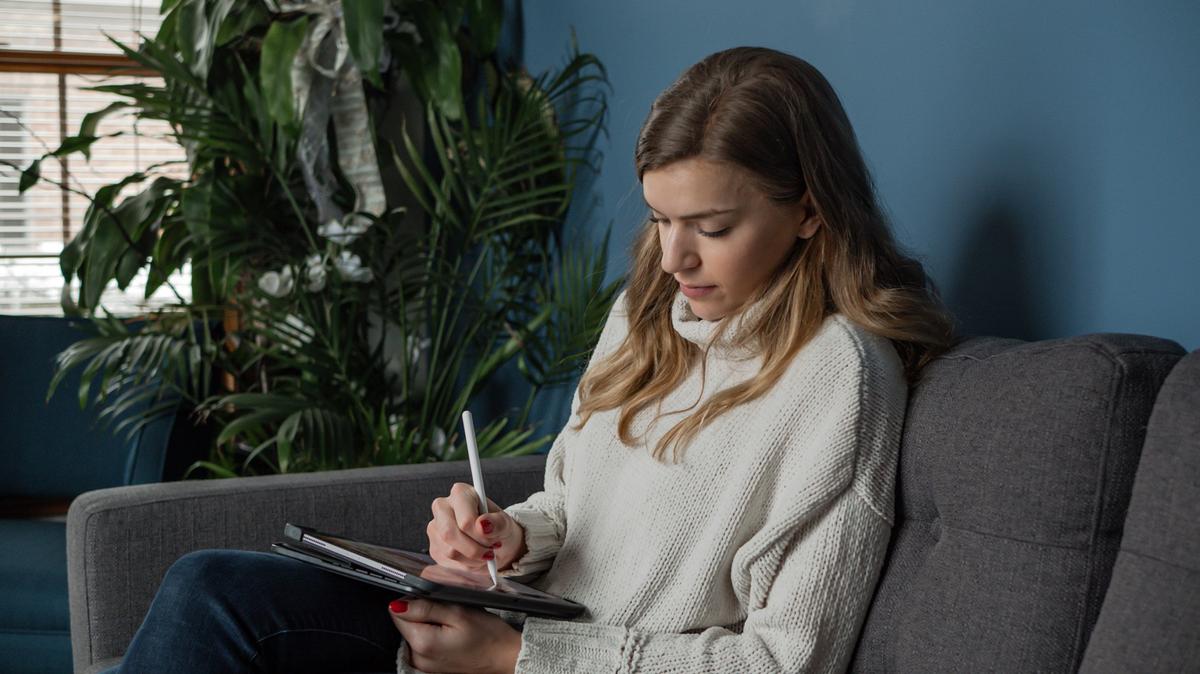 Maddie sitting on couch working on tablet with stylist