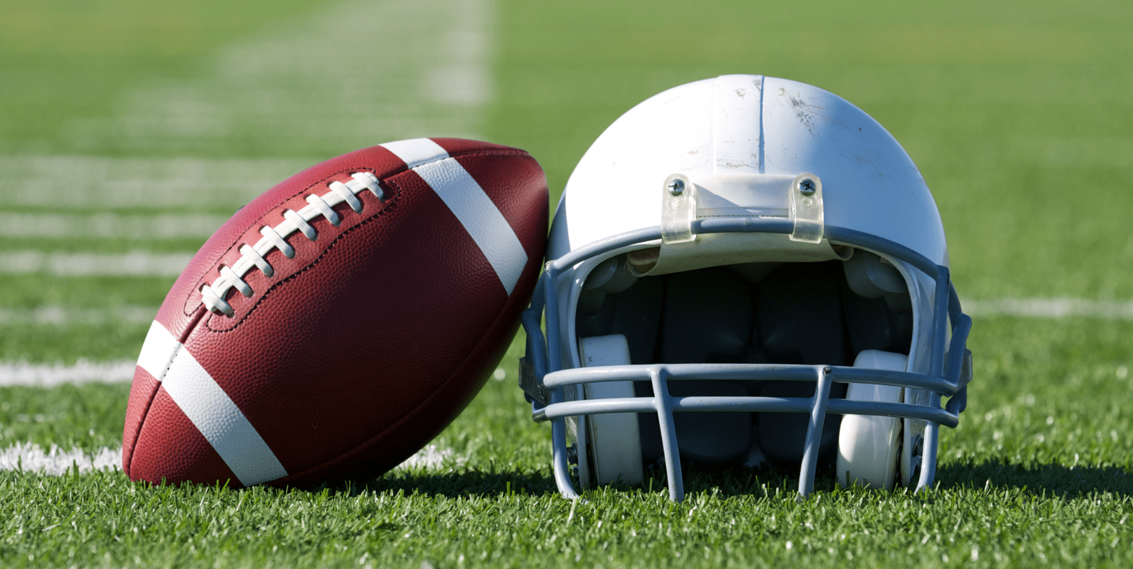 Football next to helmet on football field