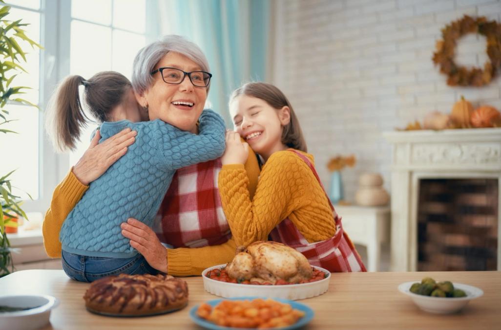 Two young girls hugging their grandmother at the dinner table