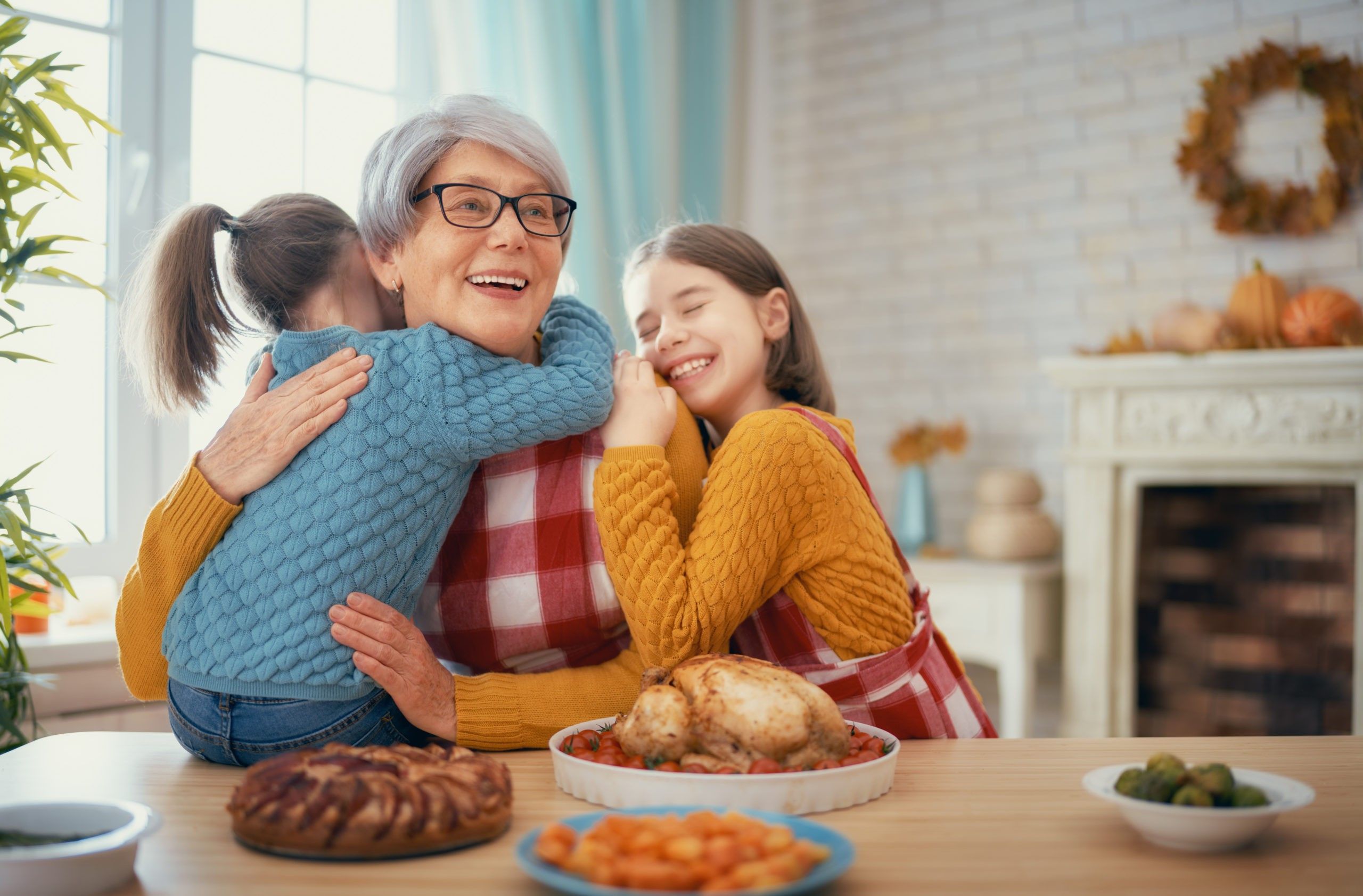 Two young girls hugging their grandmother at the dinner table