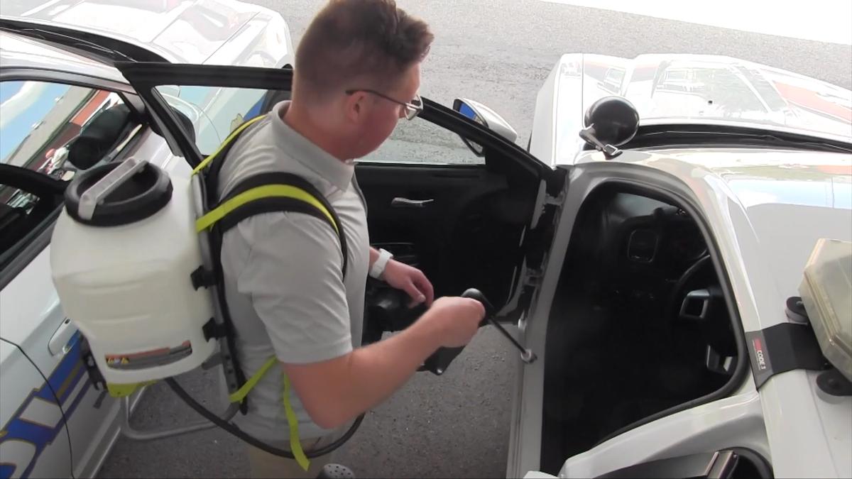 contagion-CLEAN technician disinfecting a vehicle interior with backpack sprayer