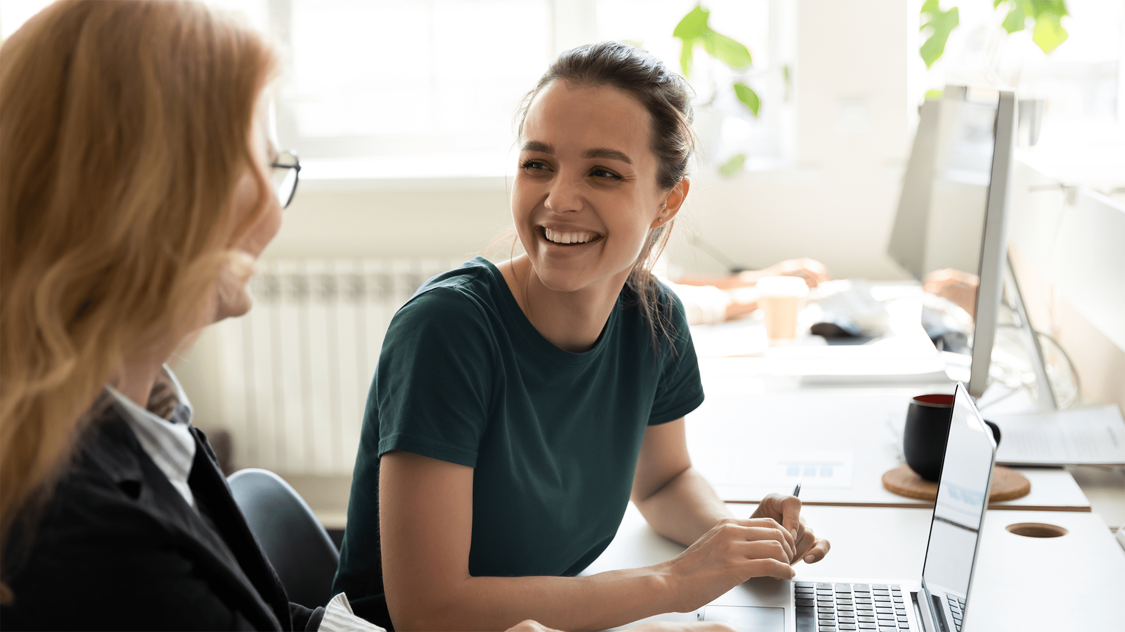 Two women smiling looking at computer screen