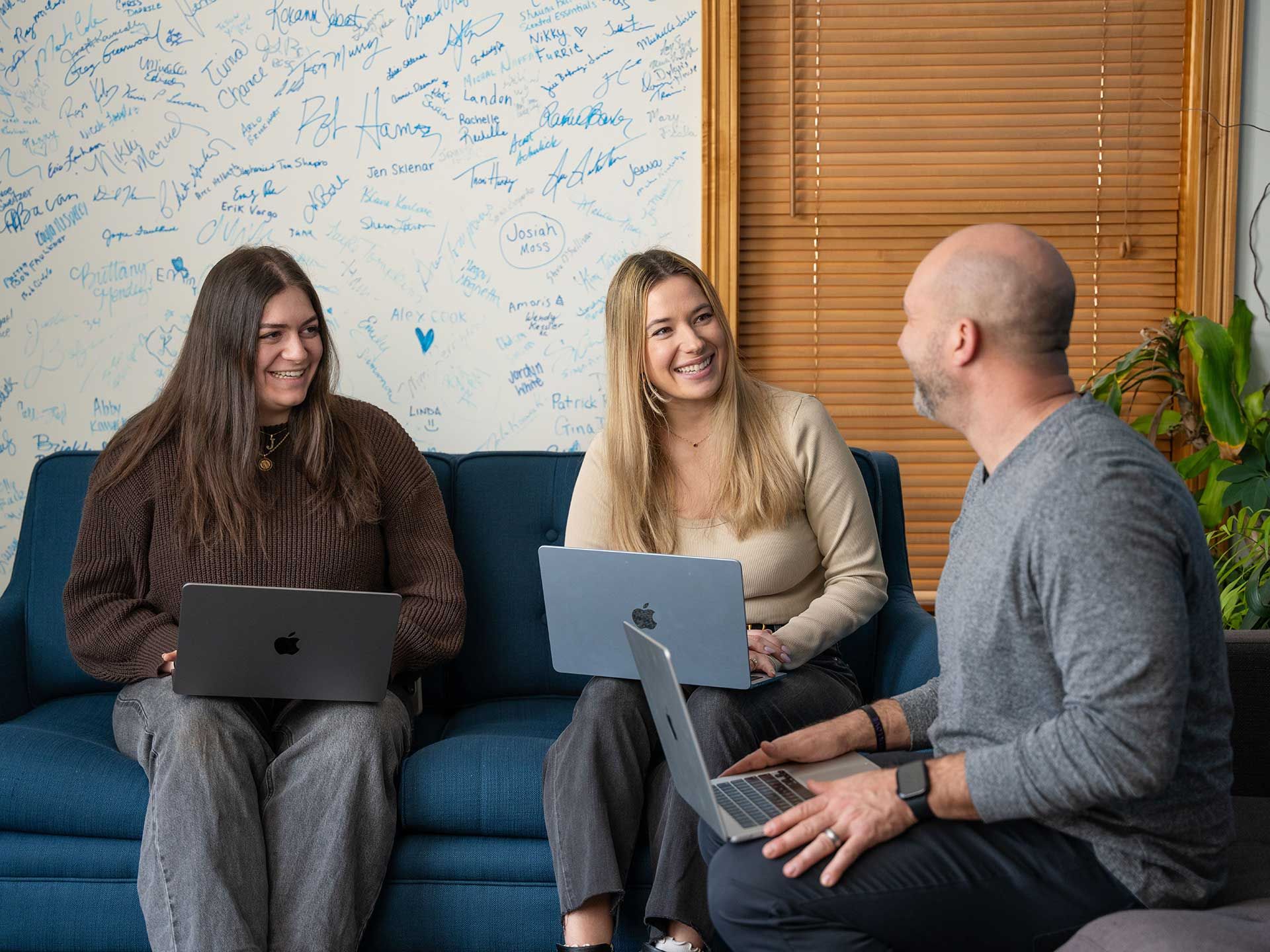 898 Marketing team collaborating on laptops in the office lounge