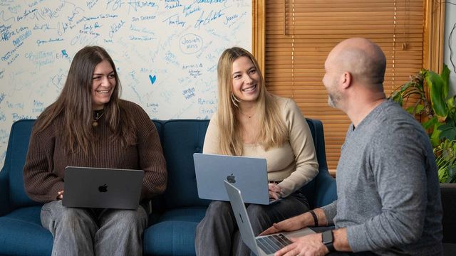 898 Marketing team collaborating on laptops in the office lounge